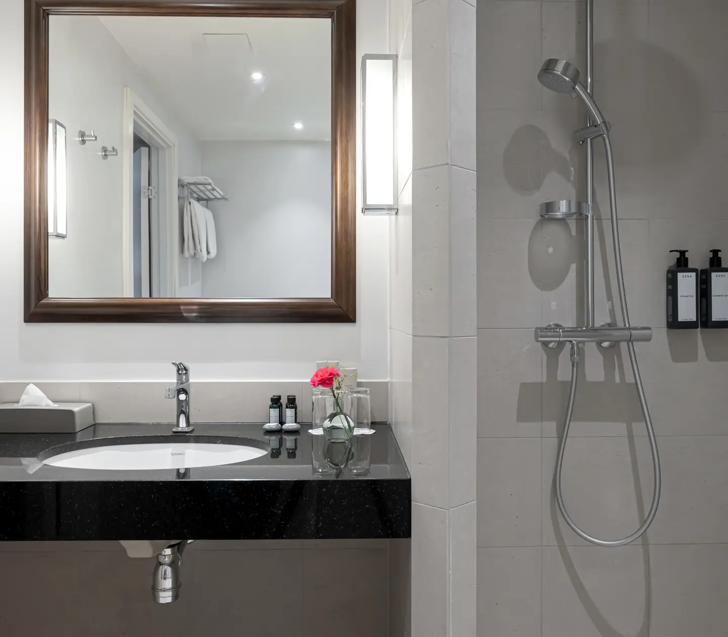 Bright bathroom with shower, sink and large mirror