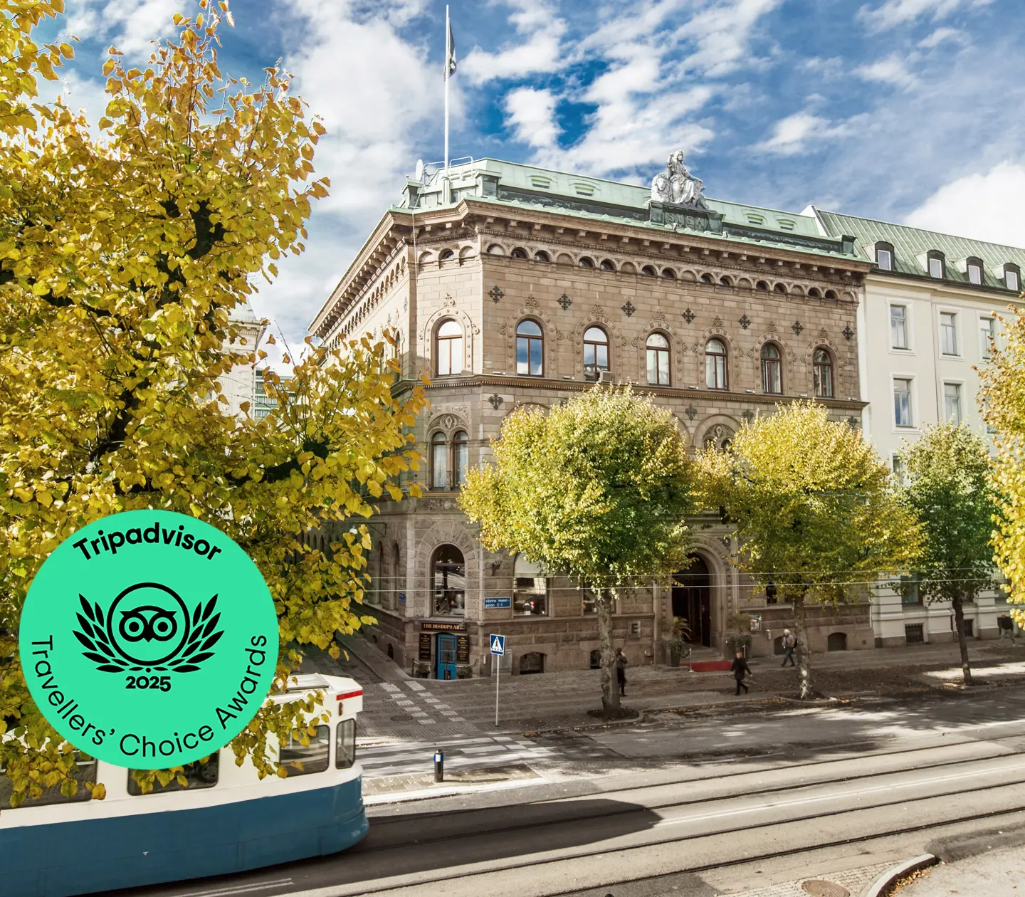 Fina fasaden av Elite Plaza Hotel i Göteborg med träd och spårvagn framför
