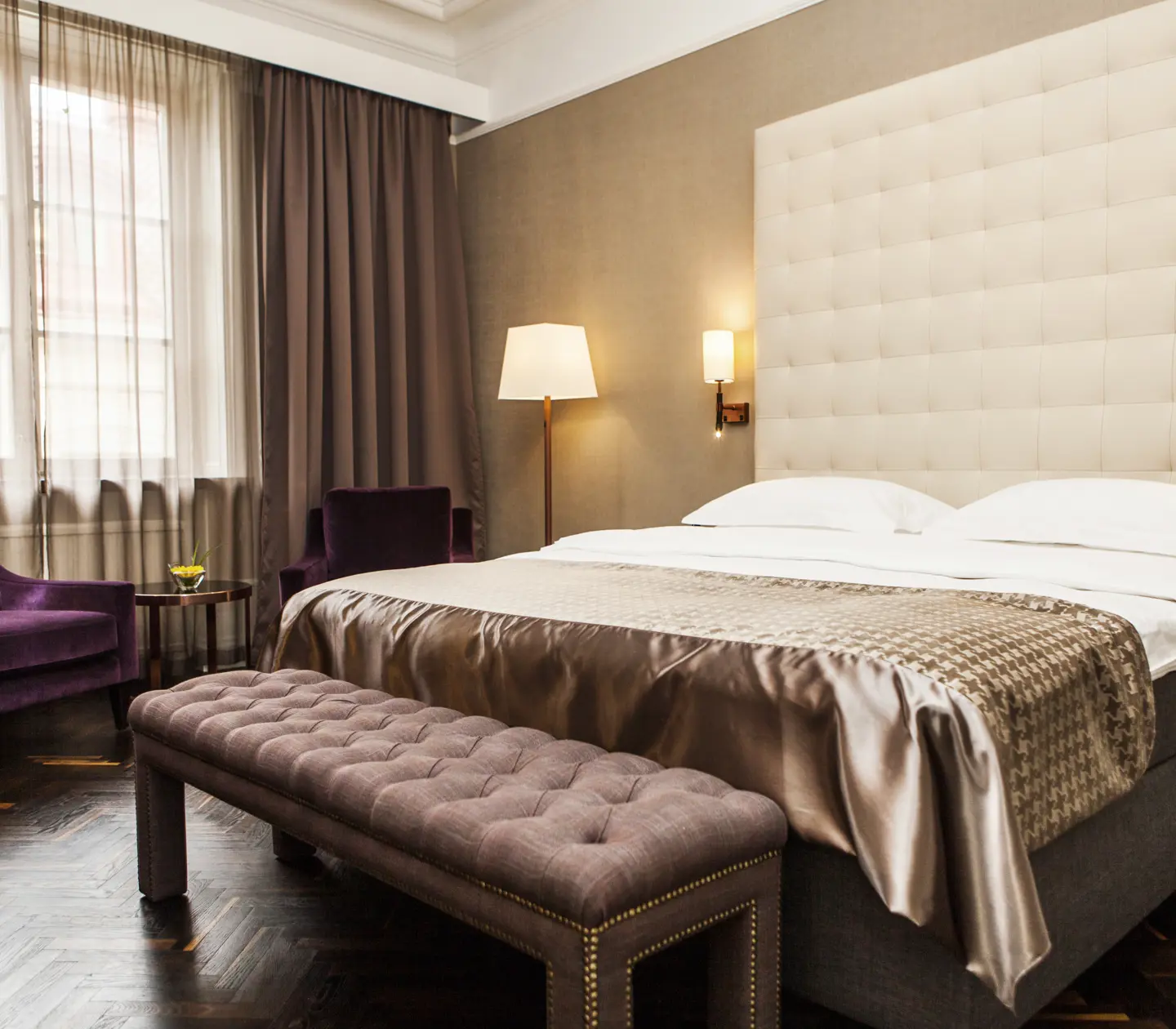 Hotel room with double bed, large headboard and armchair