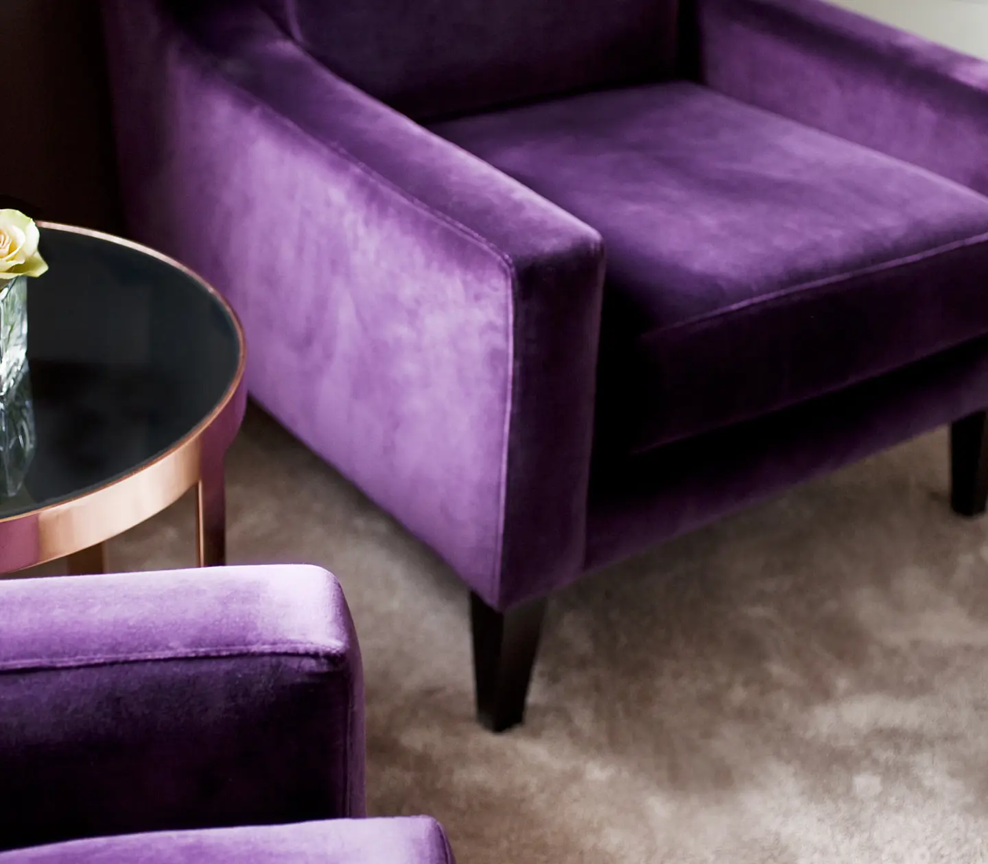 Close-up of two purple armchairs and table with rose