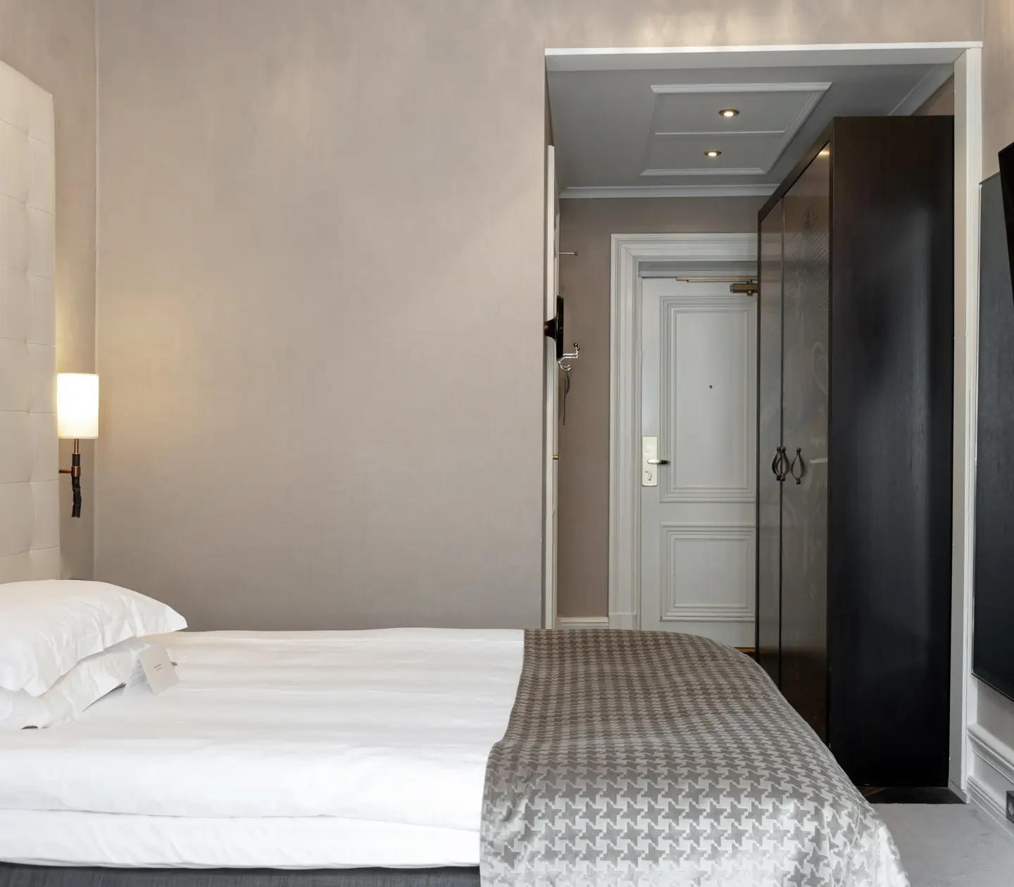 Bright hotel room with bed, TV and wardrobe