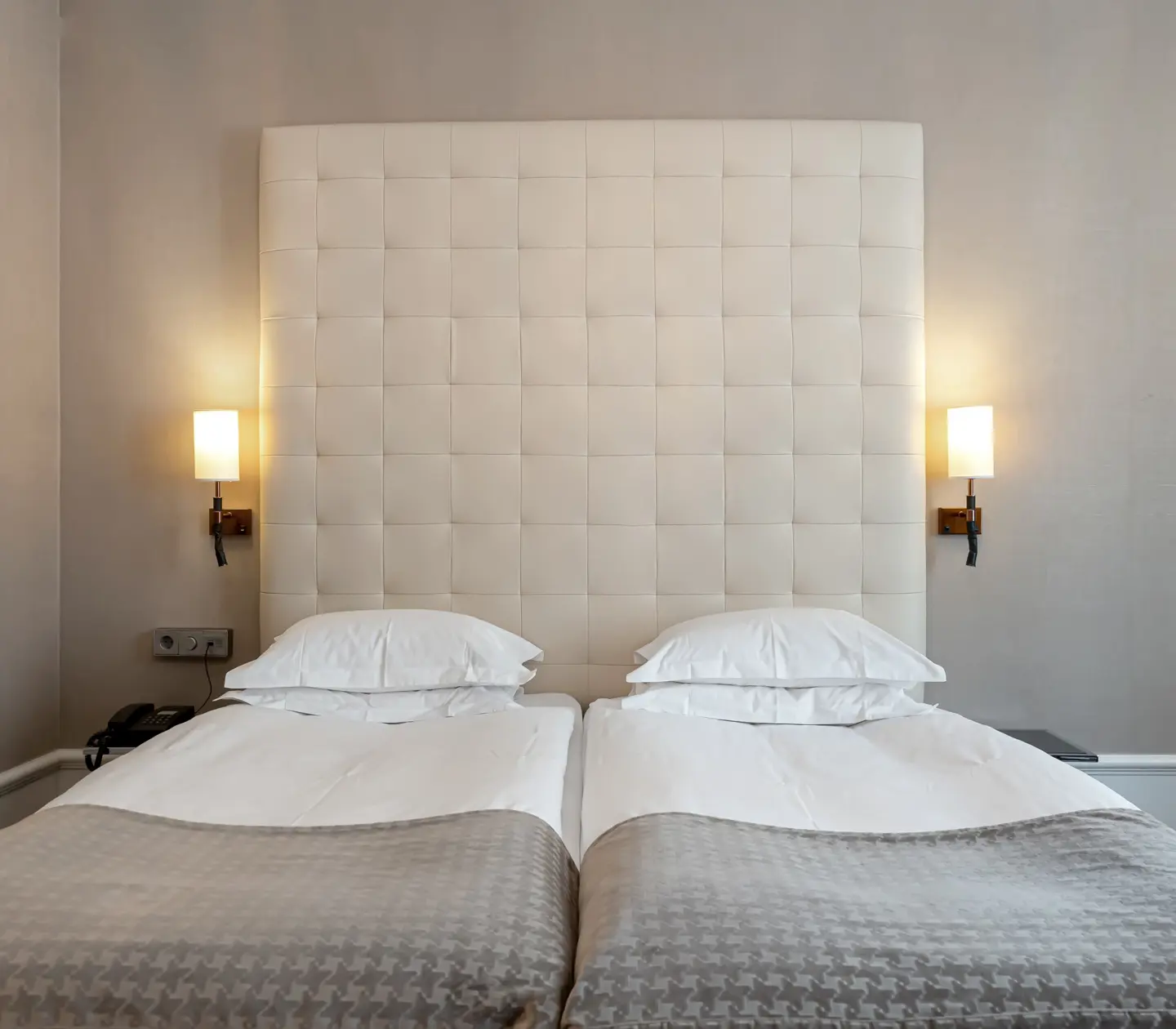 Bright hotel room with bed, large headboard and bedside lamps