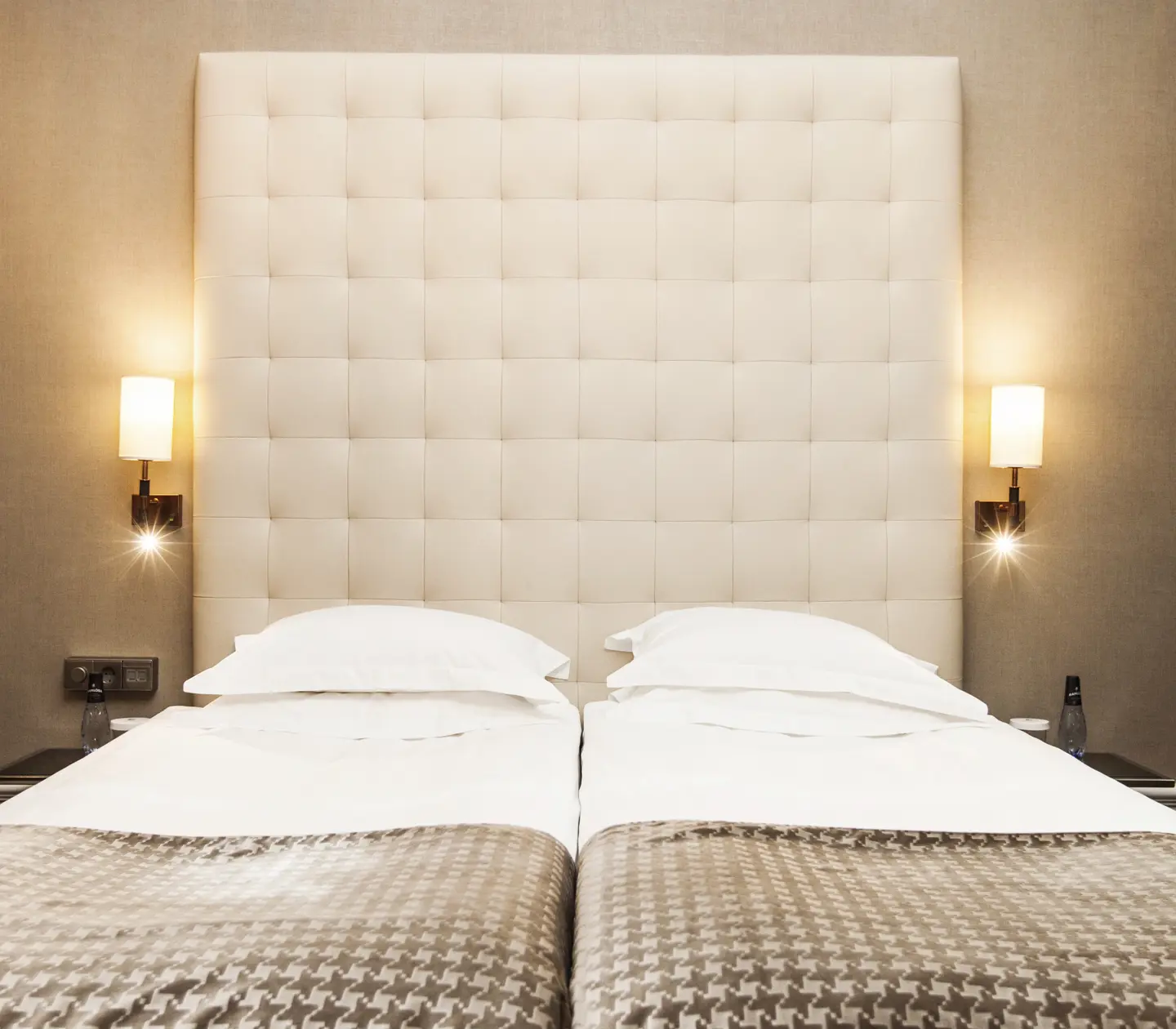 Hotel room with bed, large headboard and bedside lamps