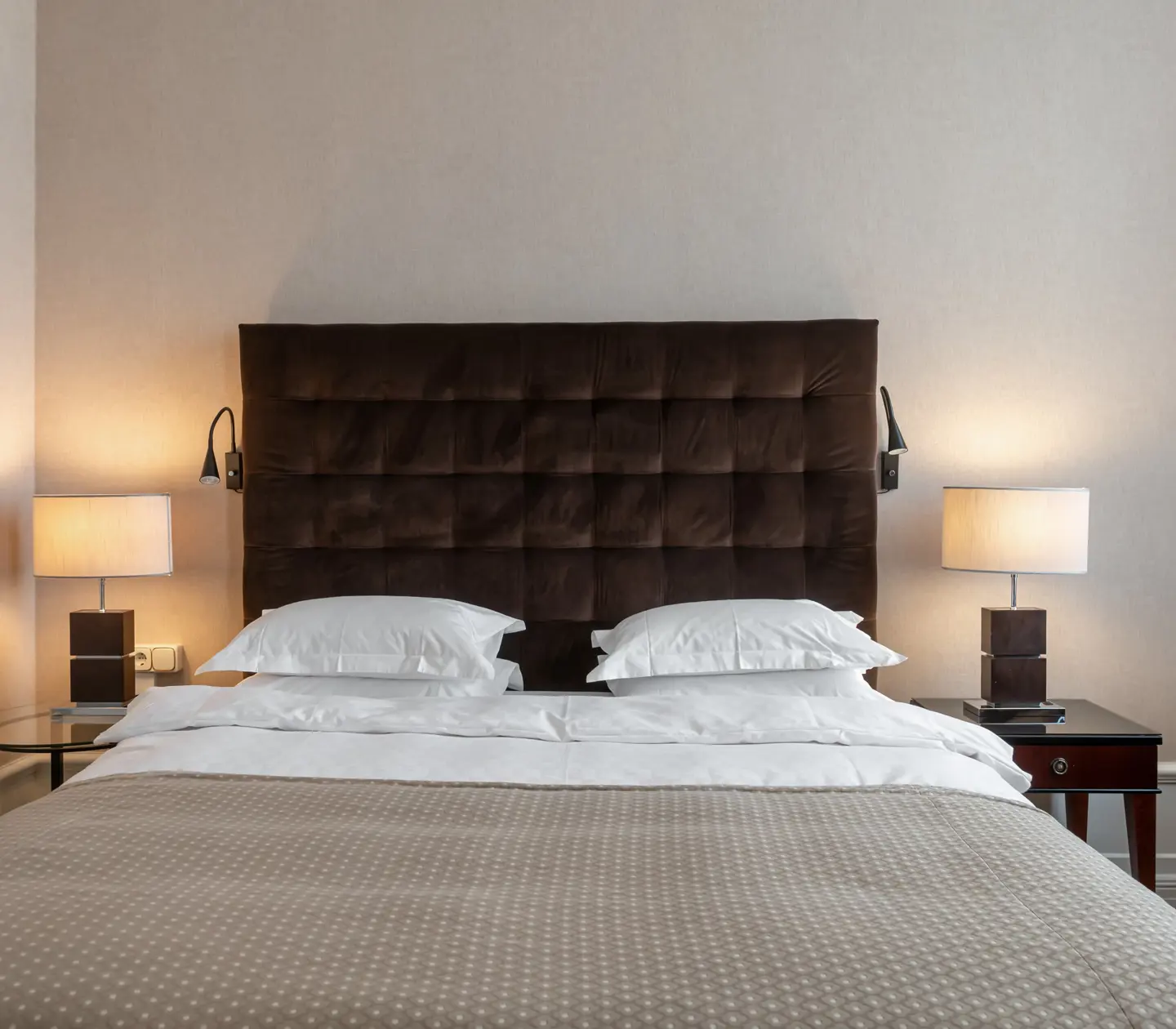 Hotel room with bed, large headboard and bedside lamps