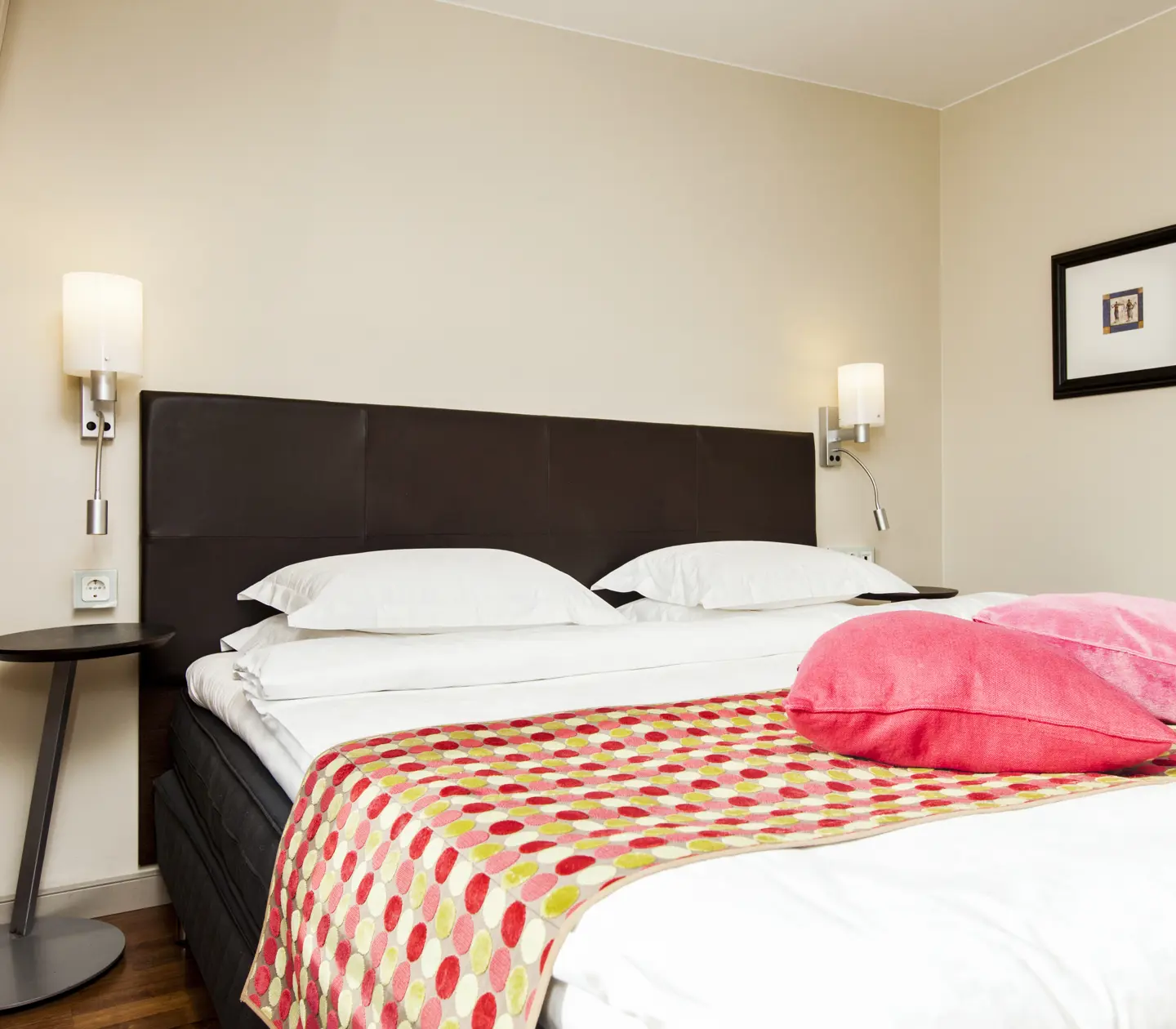 Hotel room with bed, pink pillows and bedside lamps