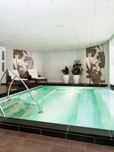 Relaxmiljö med solsängar, fönster och liten pool