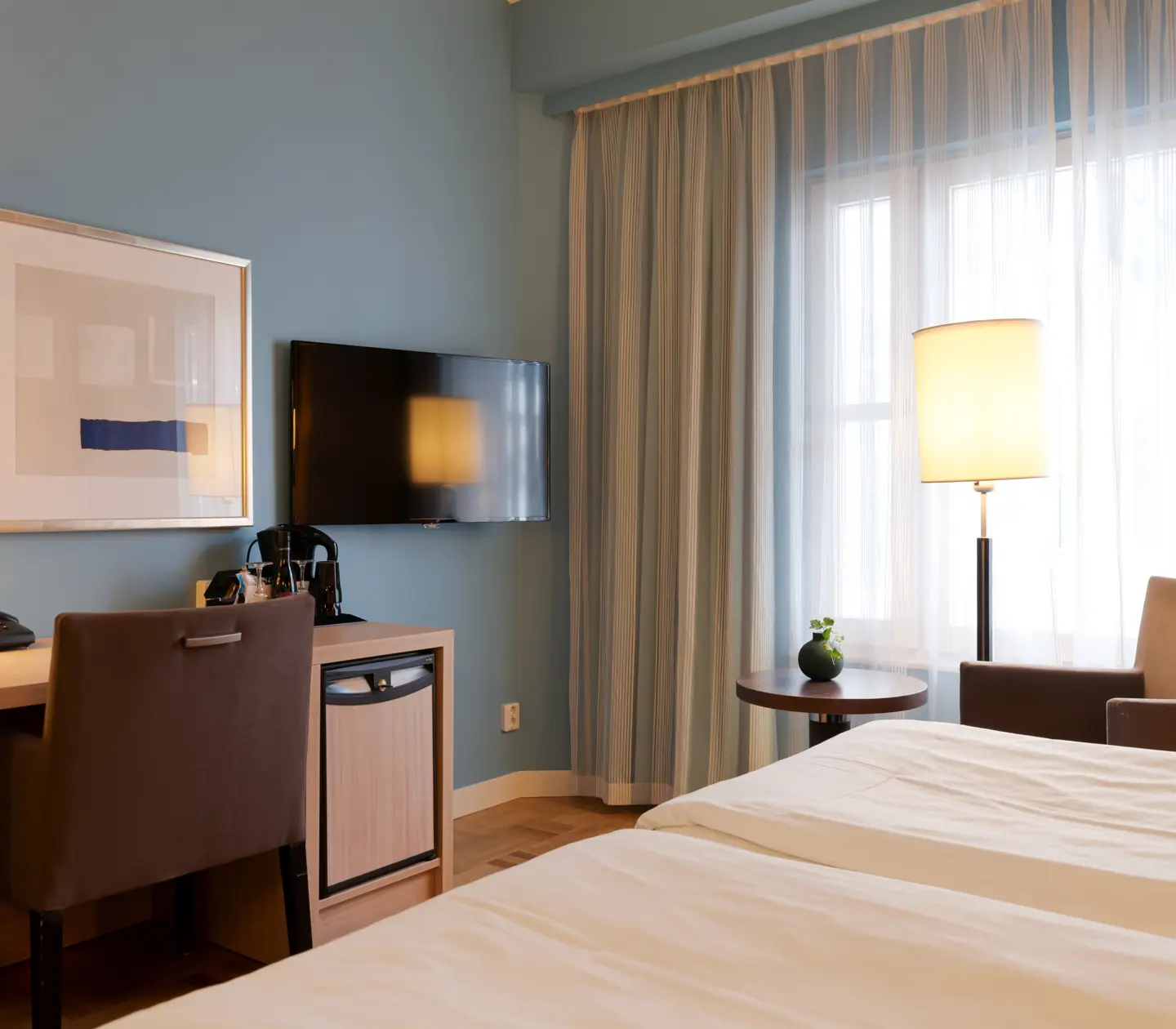 Hotel room with armchair, desk and TV