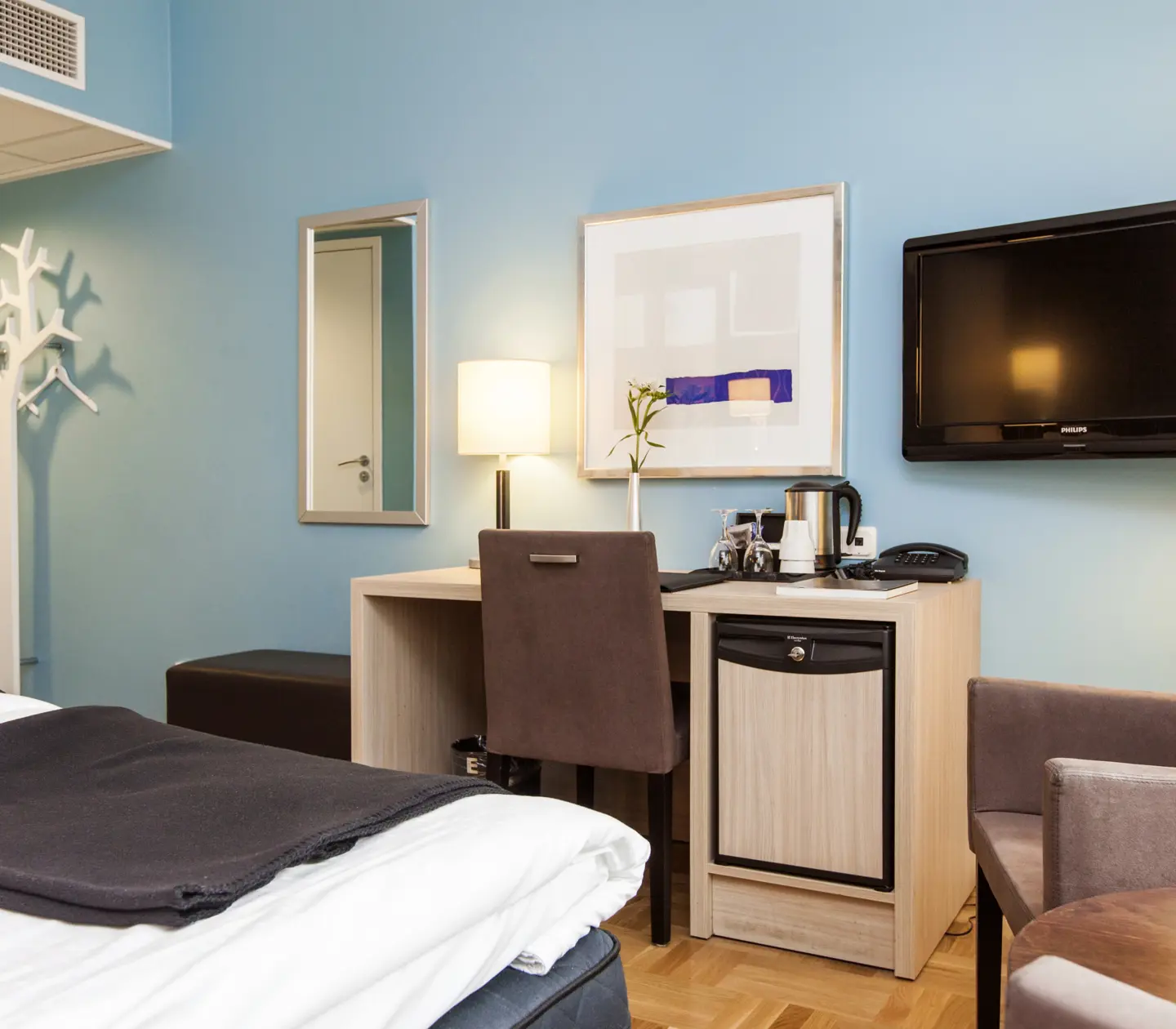 Bright hotel room with blue wall, TV and desk