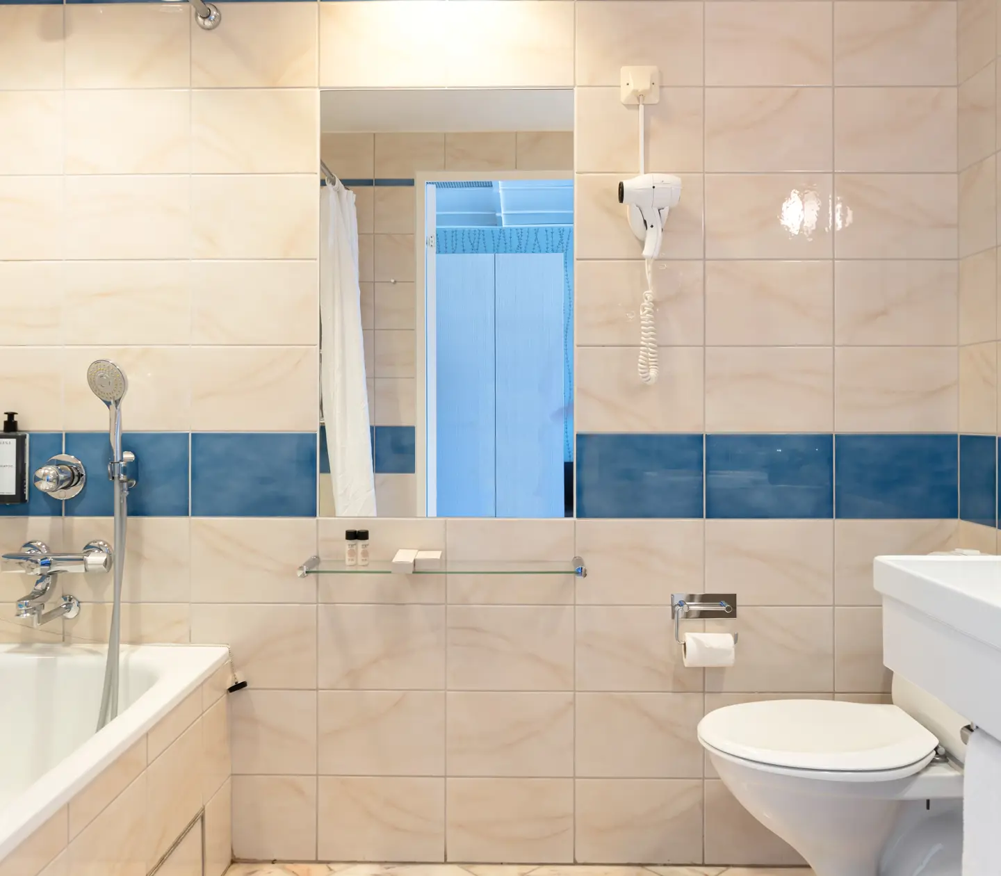 Beige bathroom with toilet, mirror and bathtub