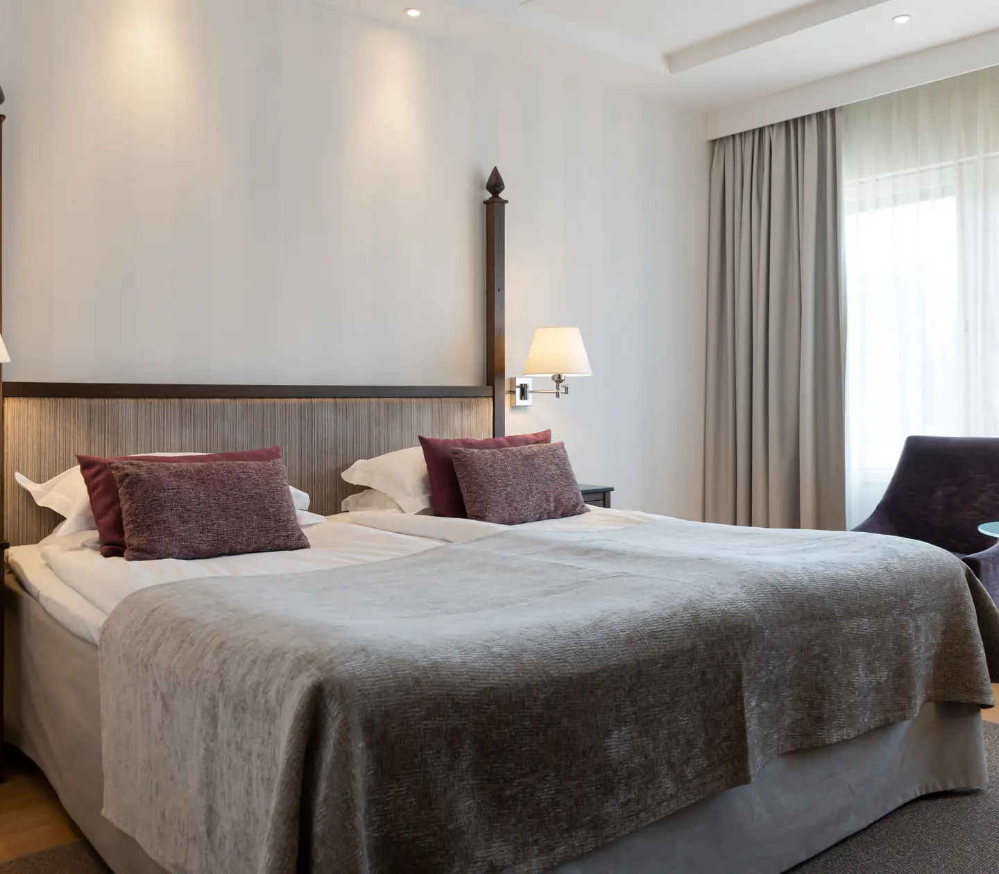 Bright hotel room with double bed, armchairs and window