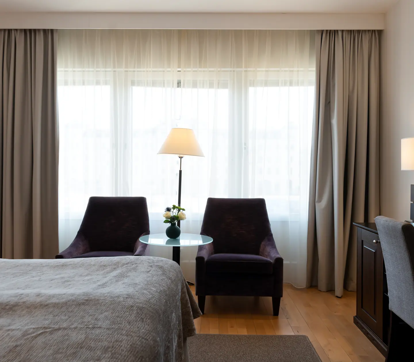 Bright hotel room with desk, armchairs and window