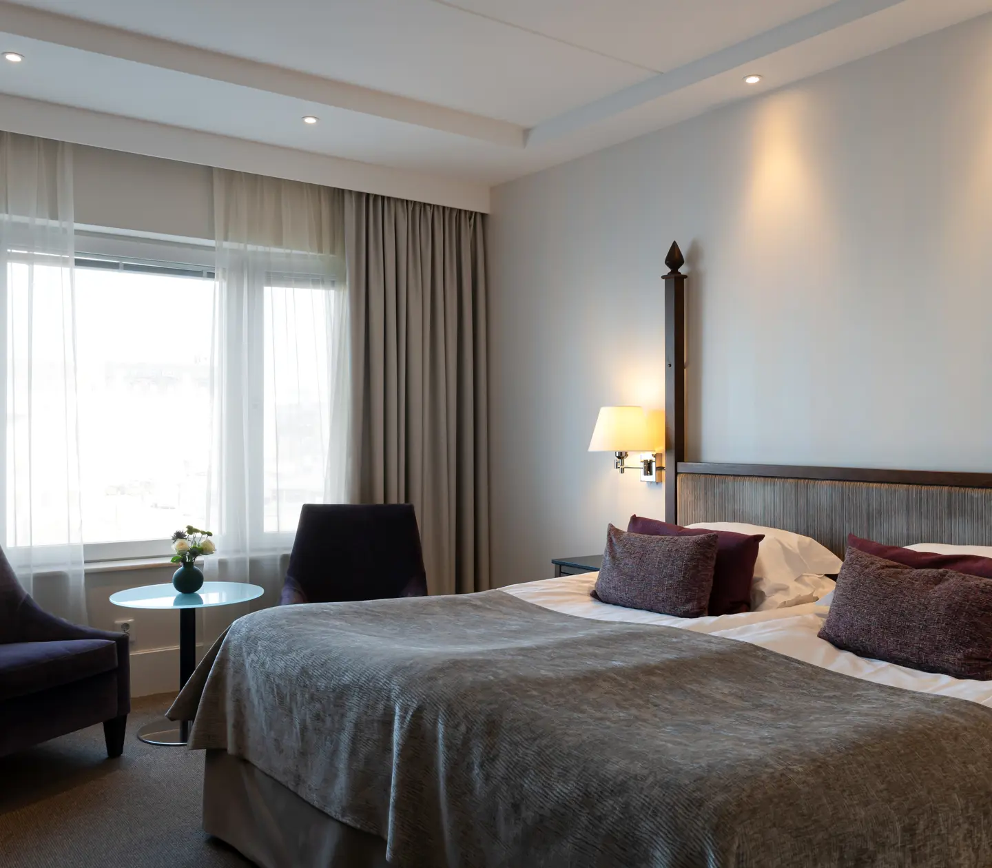 Bright hotel room with double bed, armchairs and window