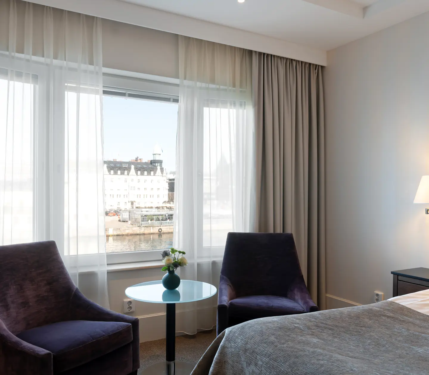 Bright hotel room with armchairs and windows overlooking the harbor