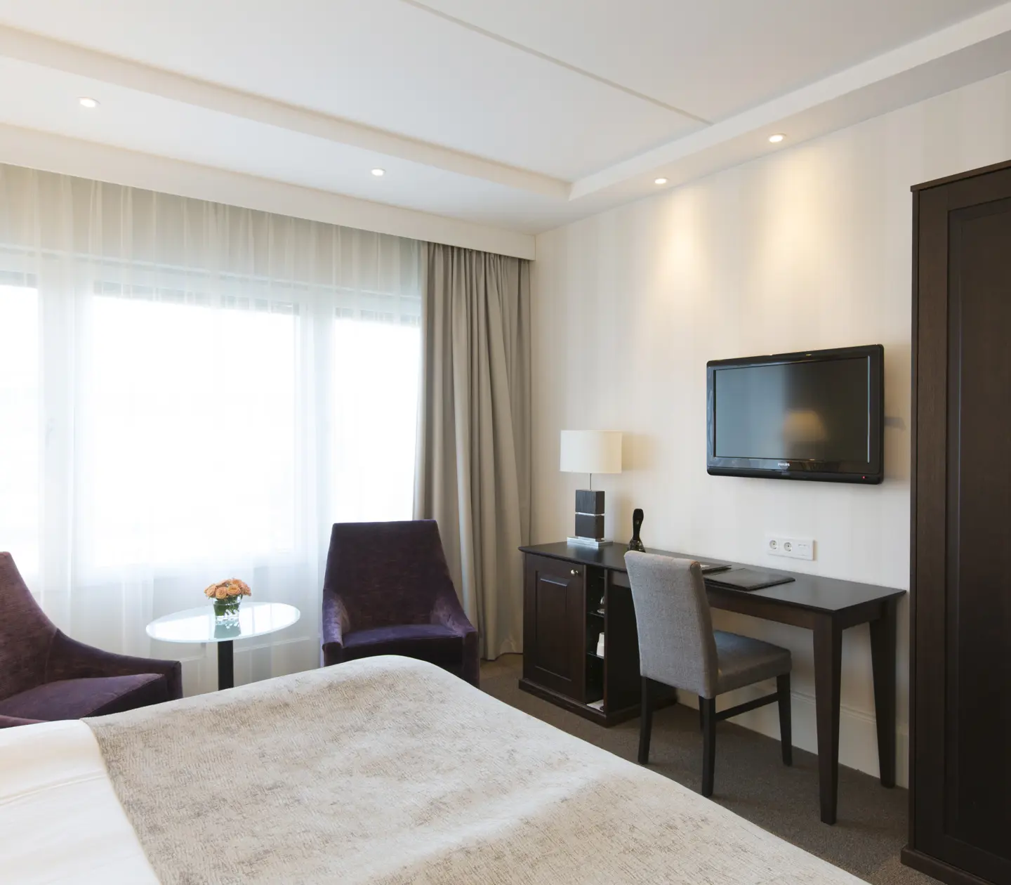 Bright hotel room with desk, armchairs and wardrobe