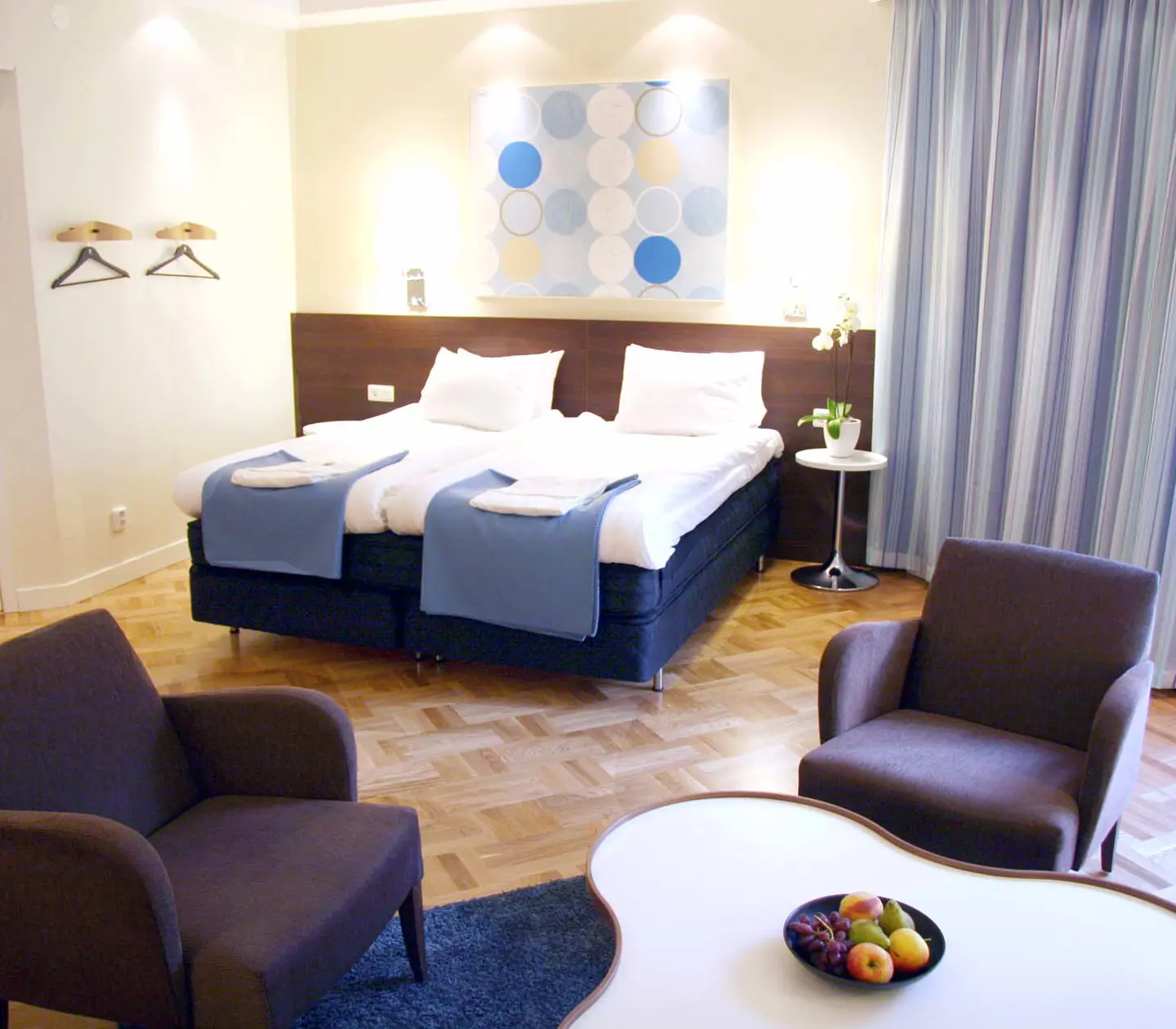 Bright hotel room with bed, armchairs and blue curtains