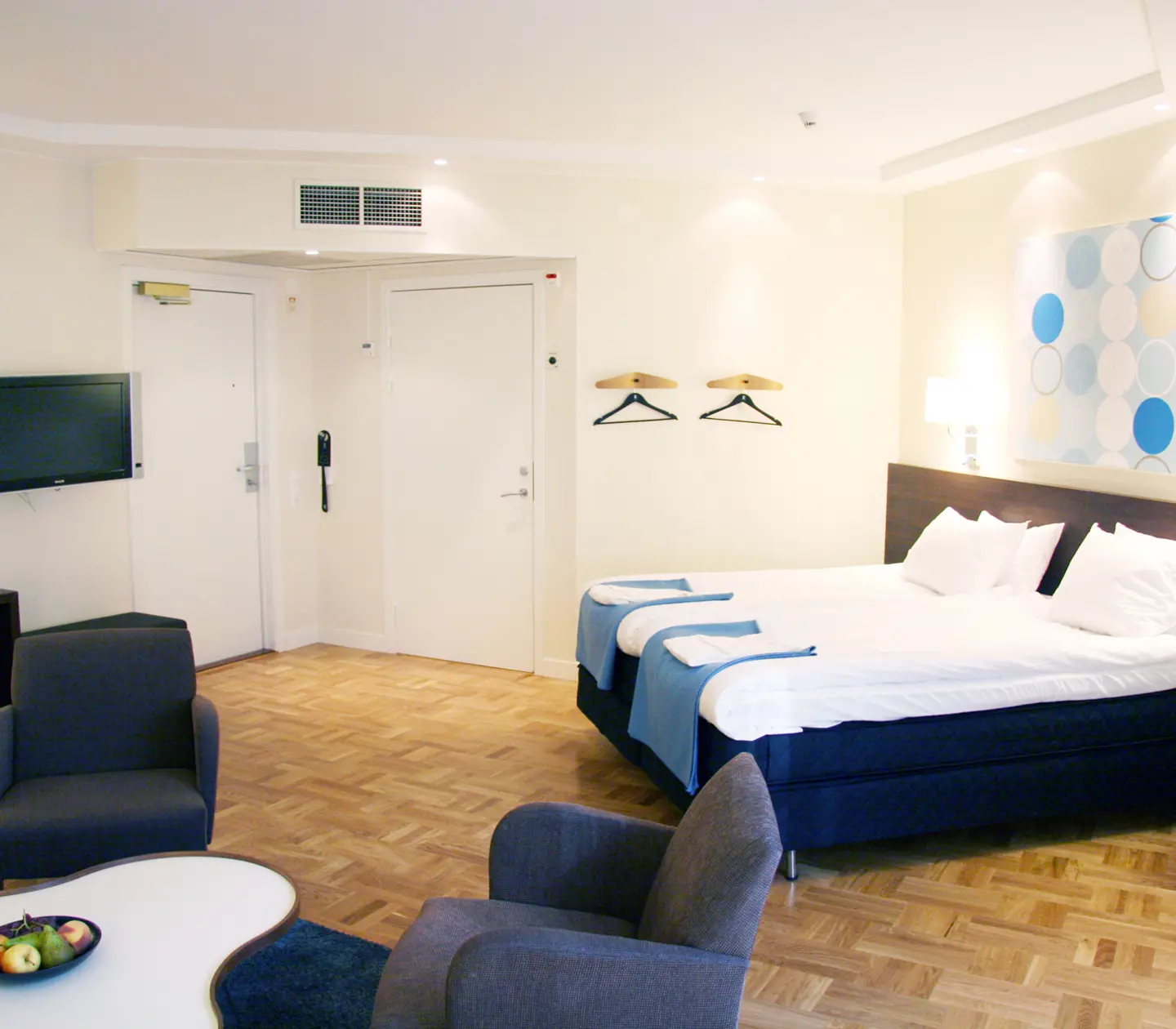 Bright hotel room with bed, armchairs and TV