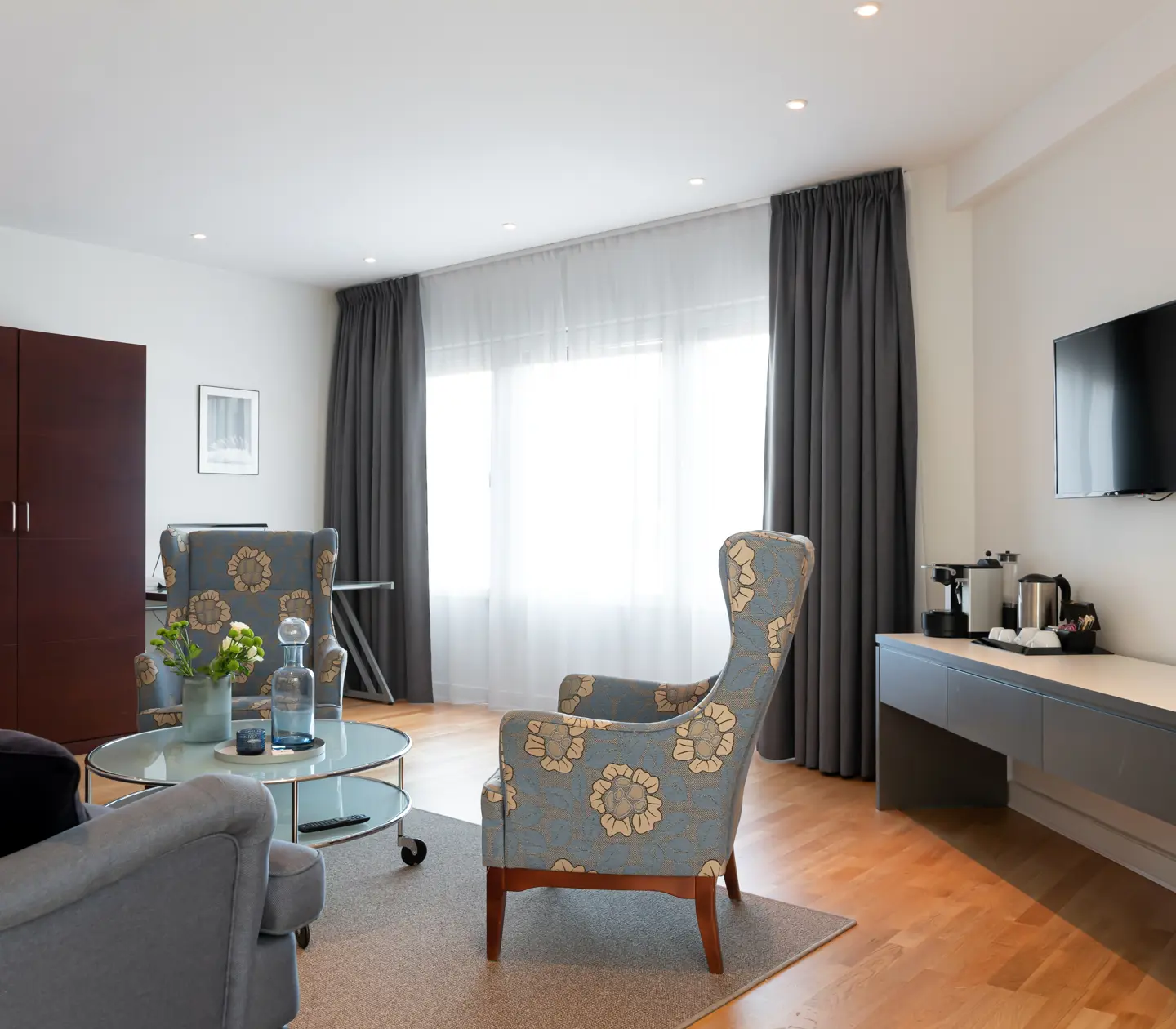 Bright hotel suite with sofa group, TV and wardrobe