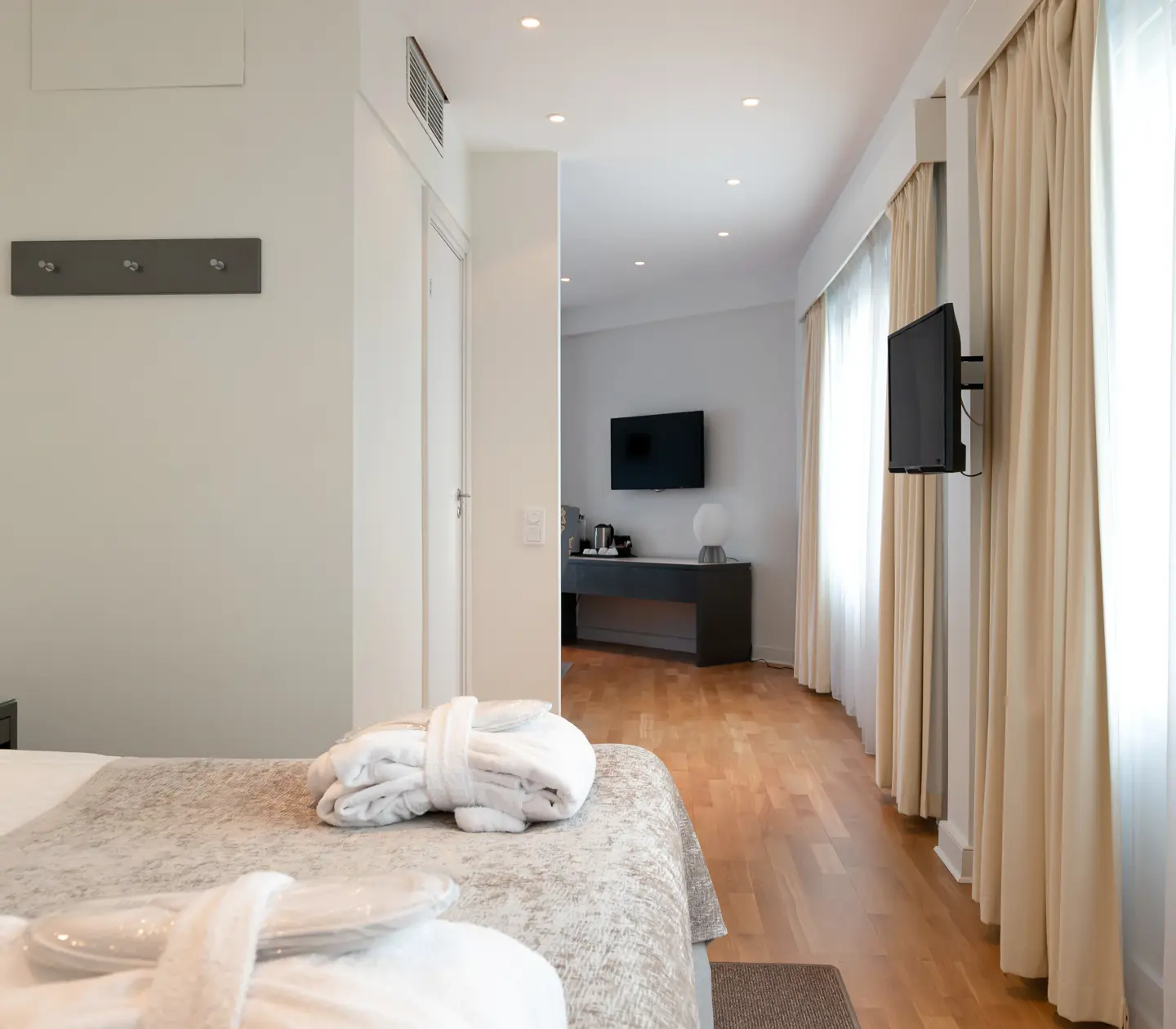 Bright hotel suite with bed, TV and window