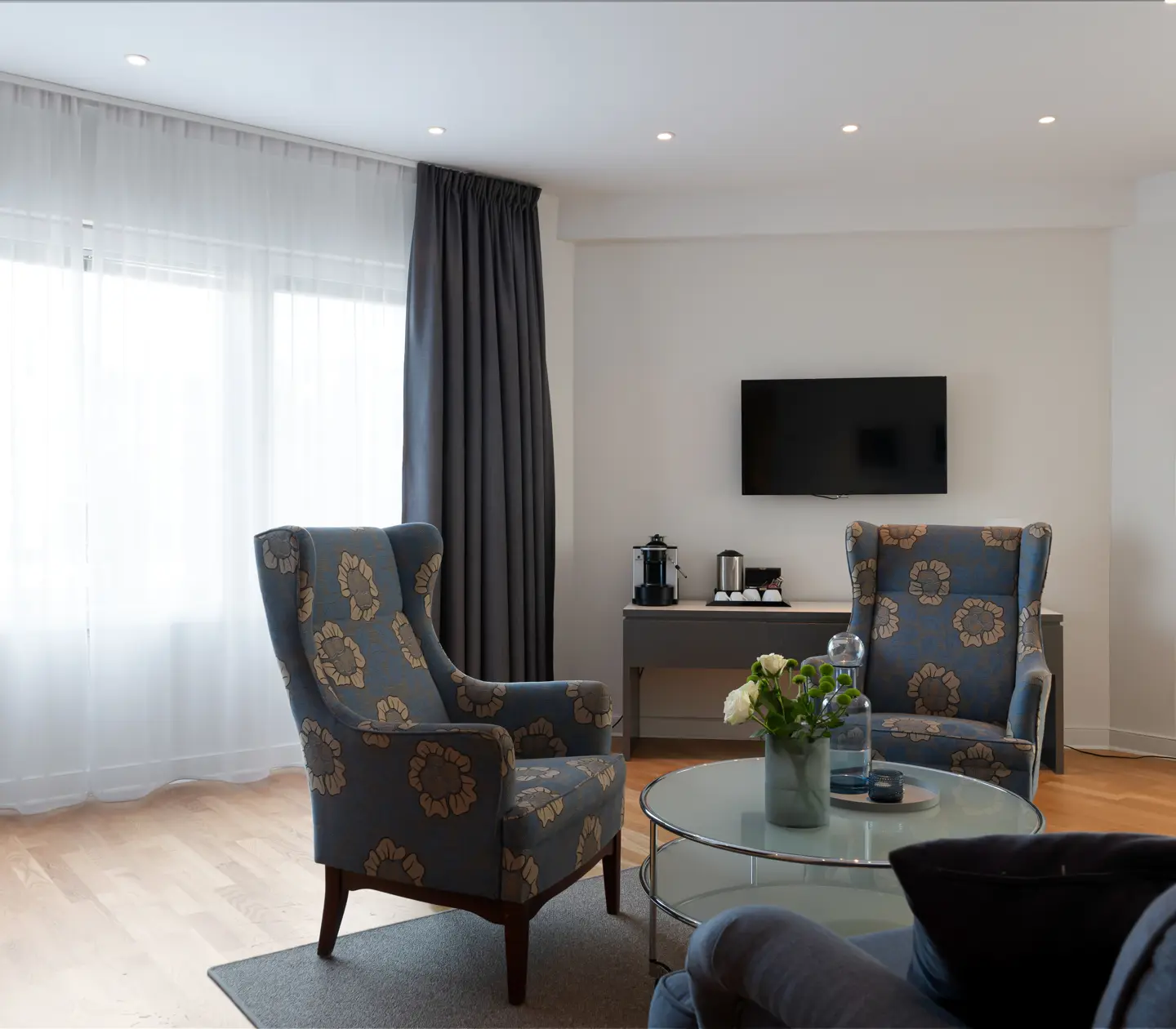 Bright hotel suite with sofa group, TV and window