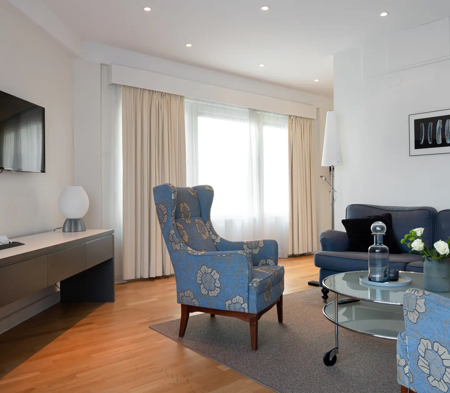 Bright hotel suite with sofa group, TV and window
