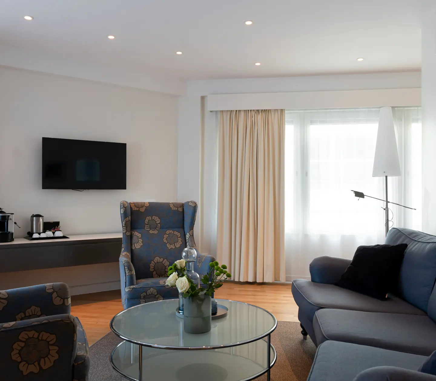 Bright hotel suite with sofa group, TV and window
