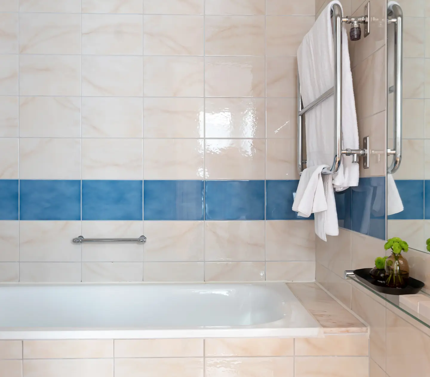 Beige bathroom with bathtub, towels and mirror