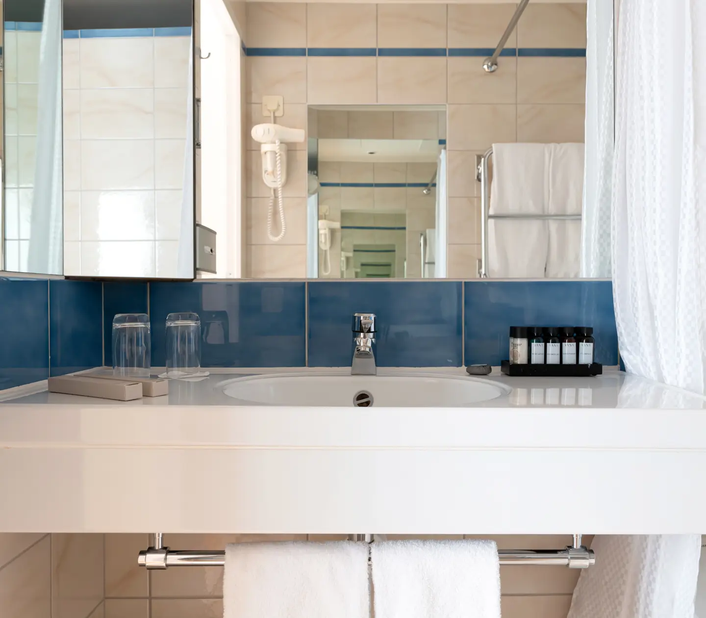 Beige bathroom with sink, mirror and towels