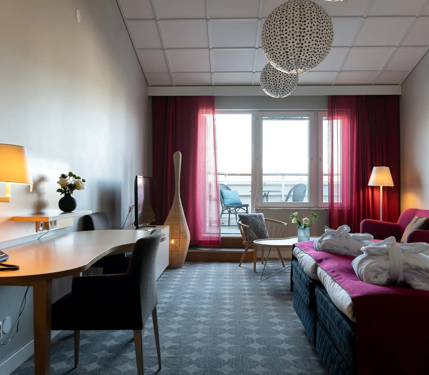 Cozy hotel suite with sofa, desk and balcony
