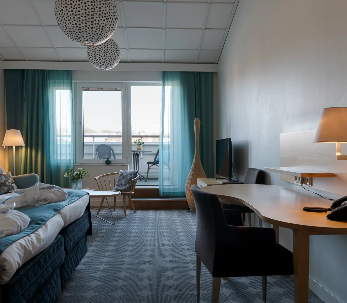 Bright hotel suite with sofa, balcony and desk