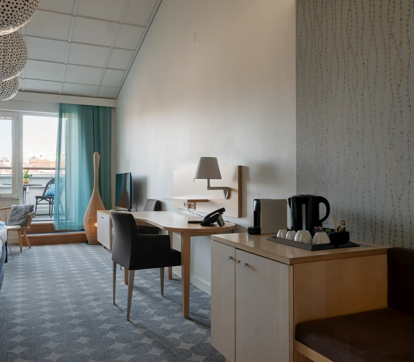 Bright hotel suite with balcony, blue curtains and desk
