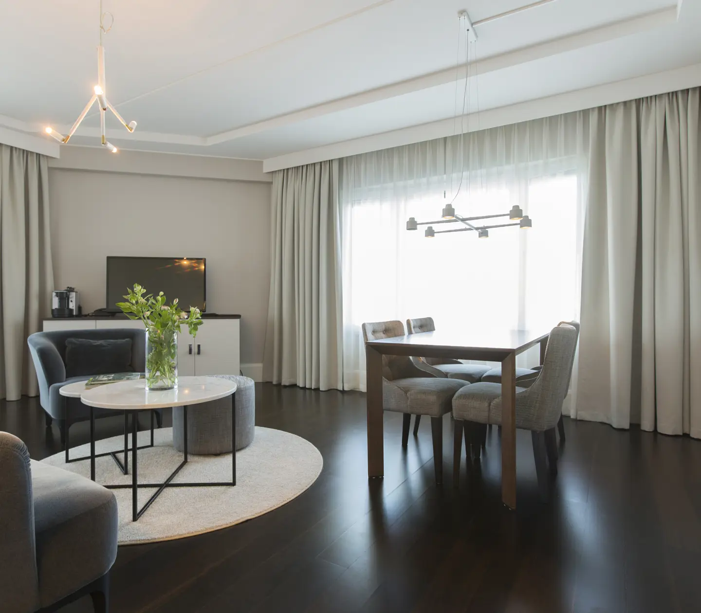 Bright hotel suite with sofa group, dining group and window