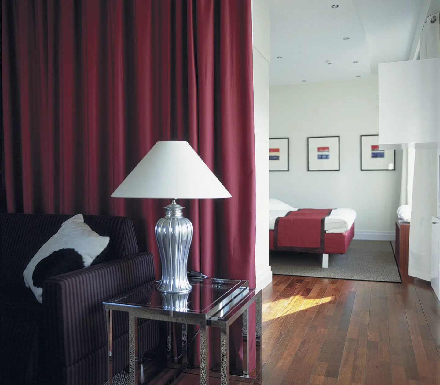 Hotel suite with bed, table lamp and paintings