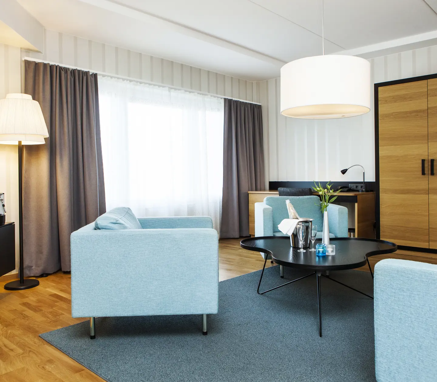 Hotel suite with blue sofa group, desk and wardrobe