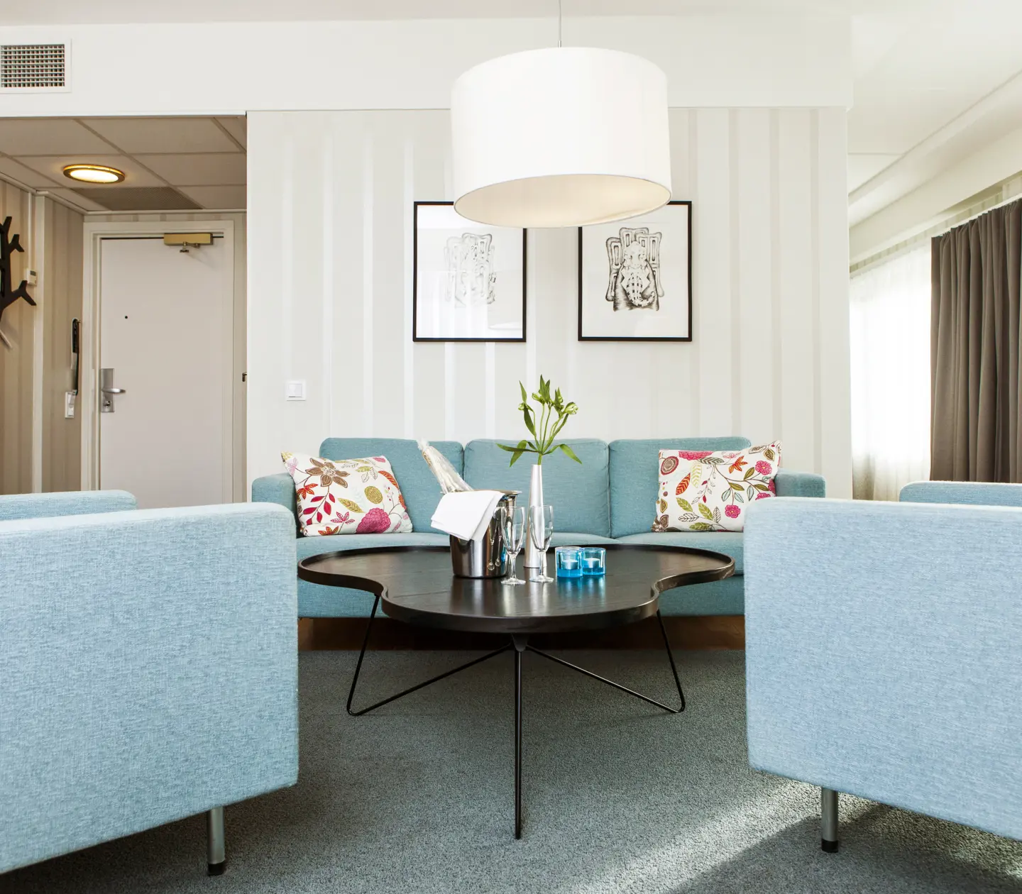 Bright hotel suite with blue sofa group, windows and paintings