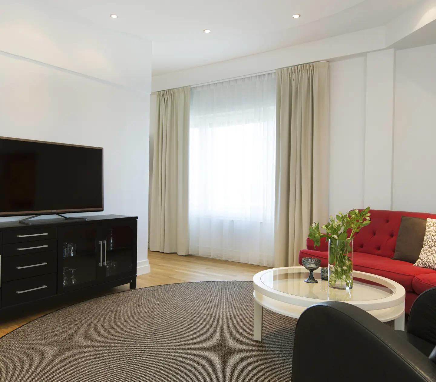 Bright hotel suite with sofa group, TV and window