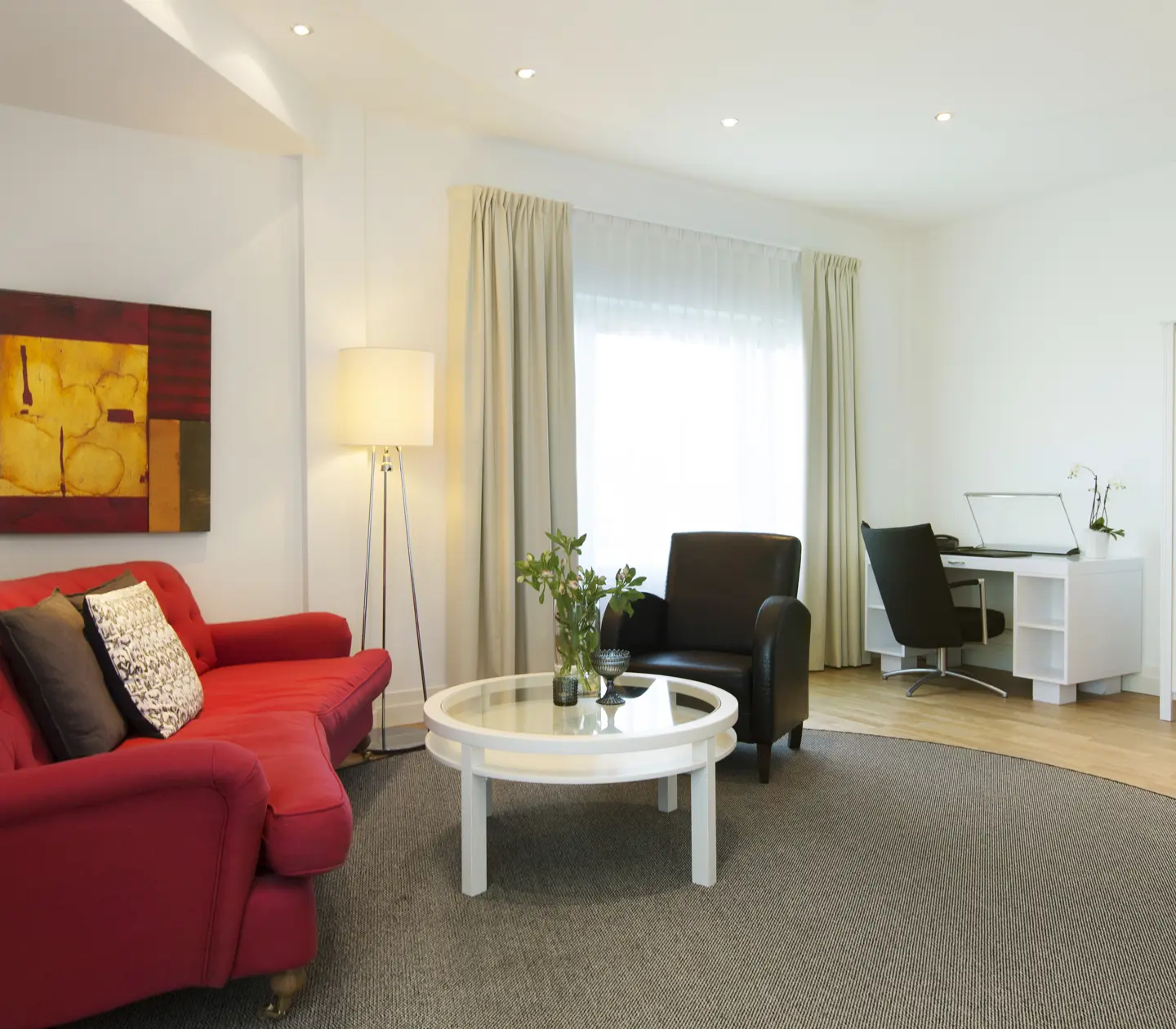 Bright hotel suite with sofa group, desk and window