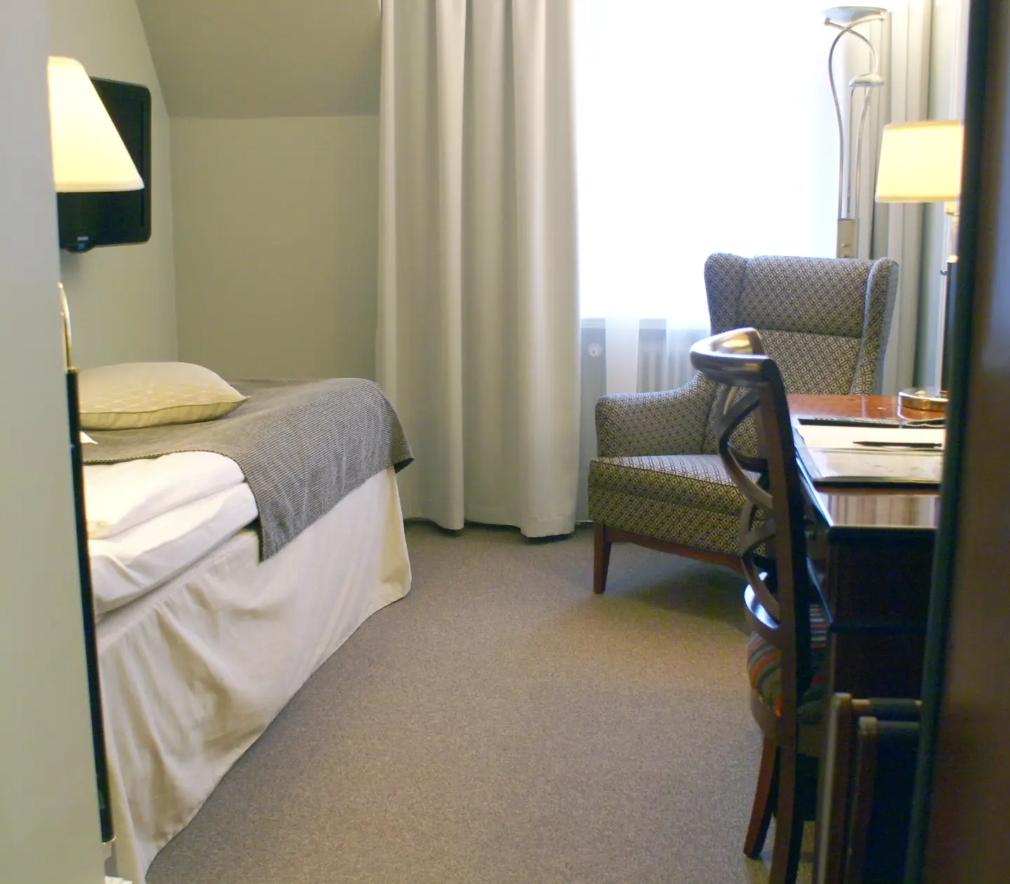 Hotel room with single bed, armchair and desk