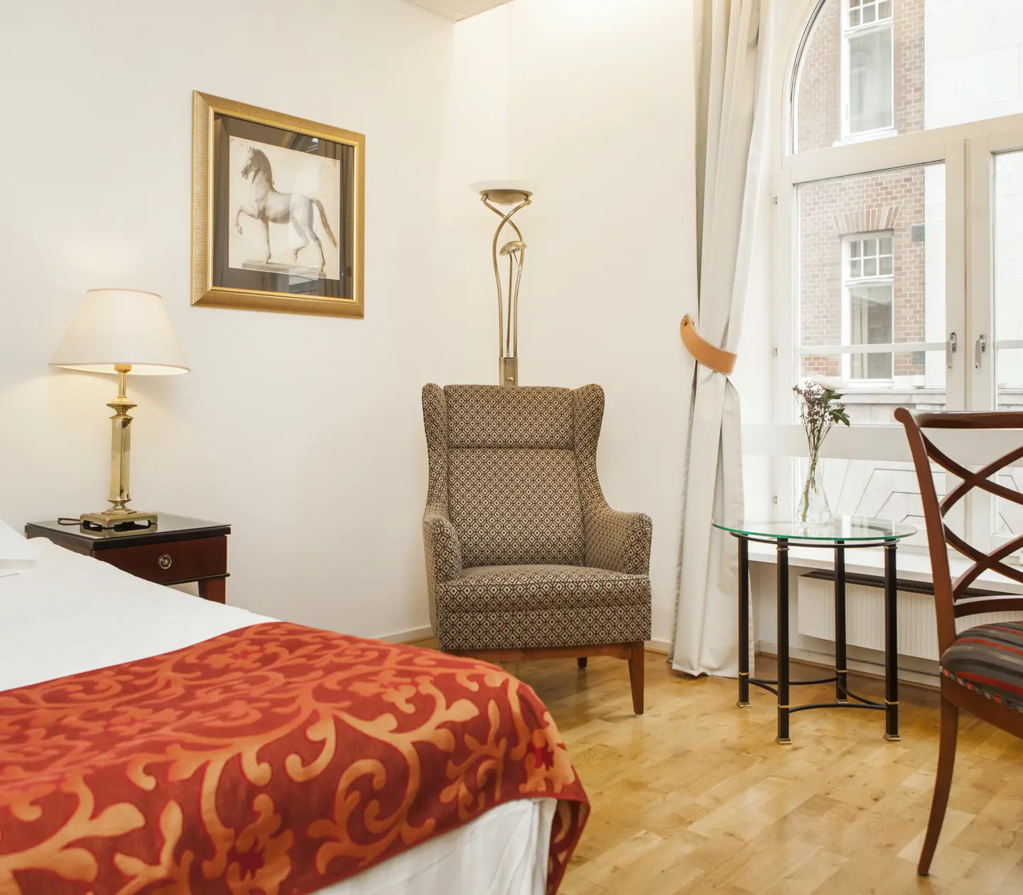 Bright hotel room with bed, armchair and window