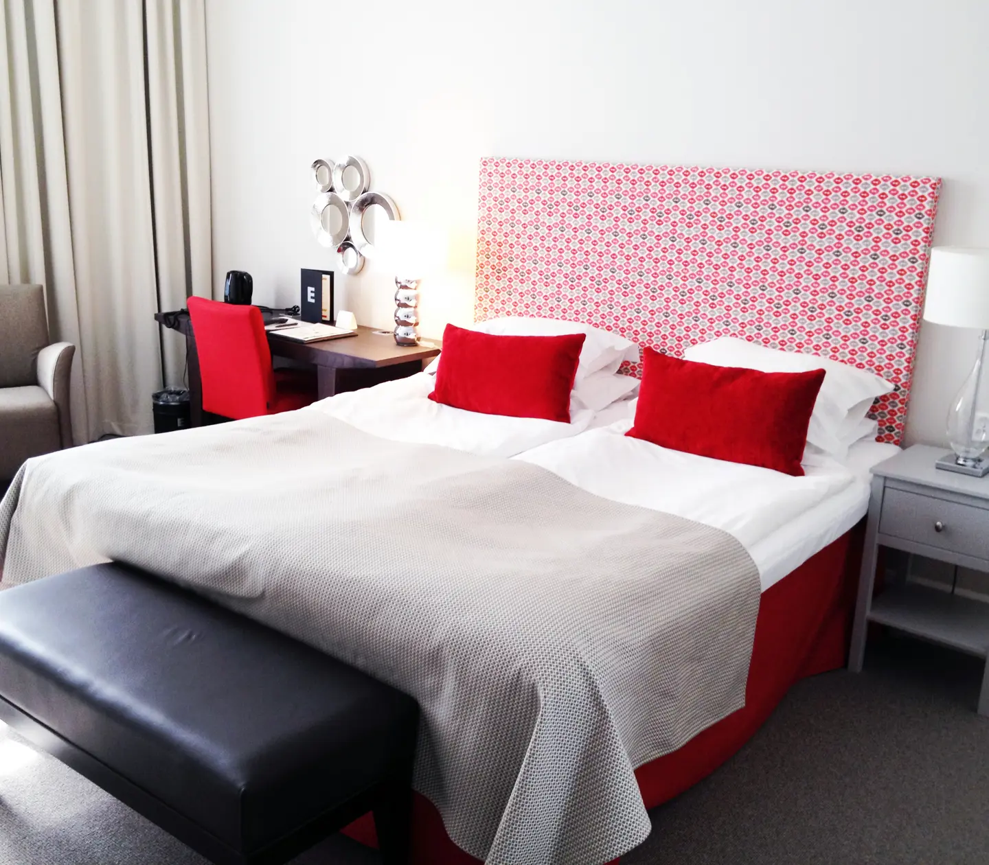 Hotel room with double bed, red headboard and desk