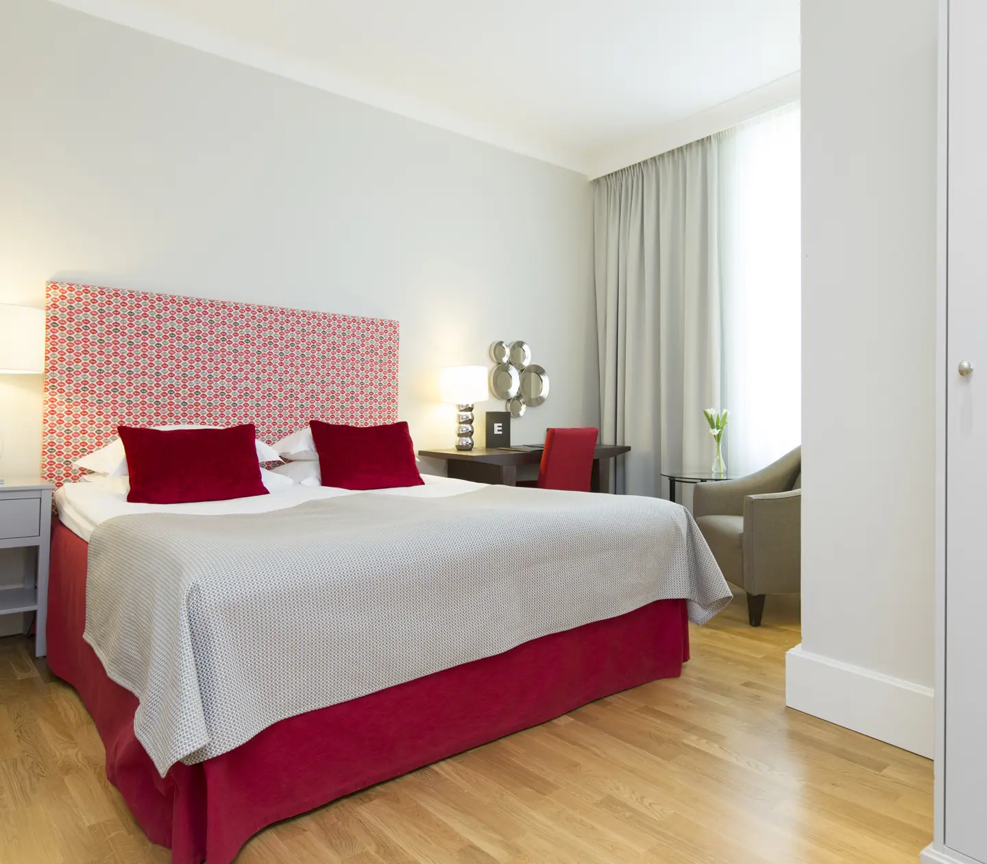 Hotel room with double bed, red headboard and desk