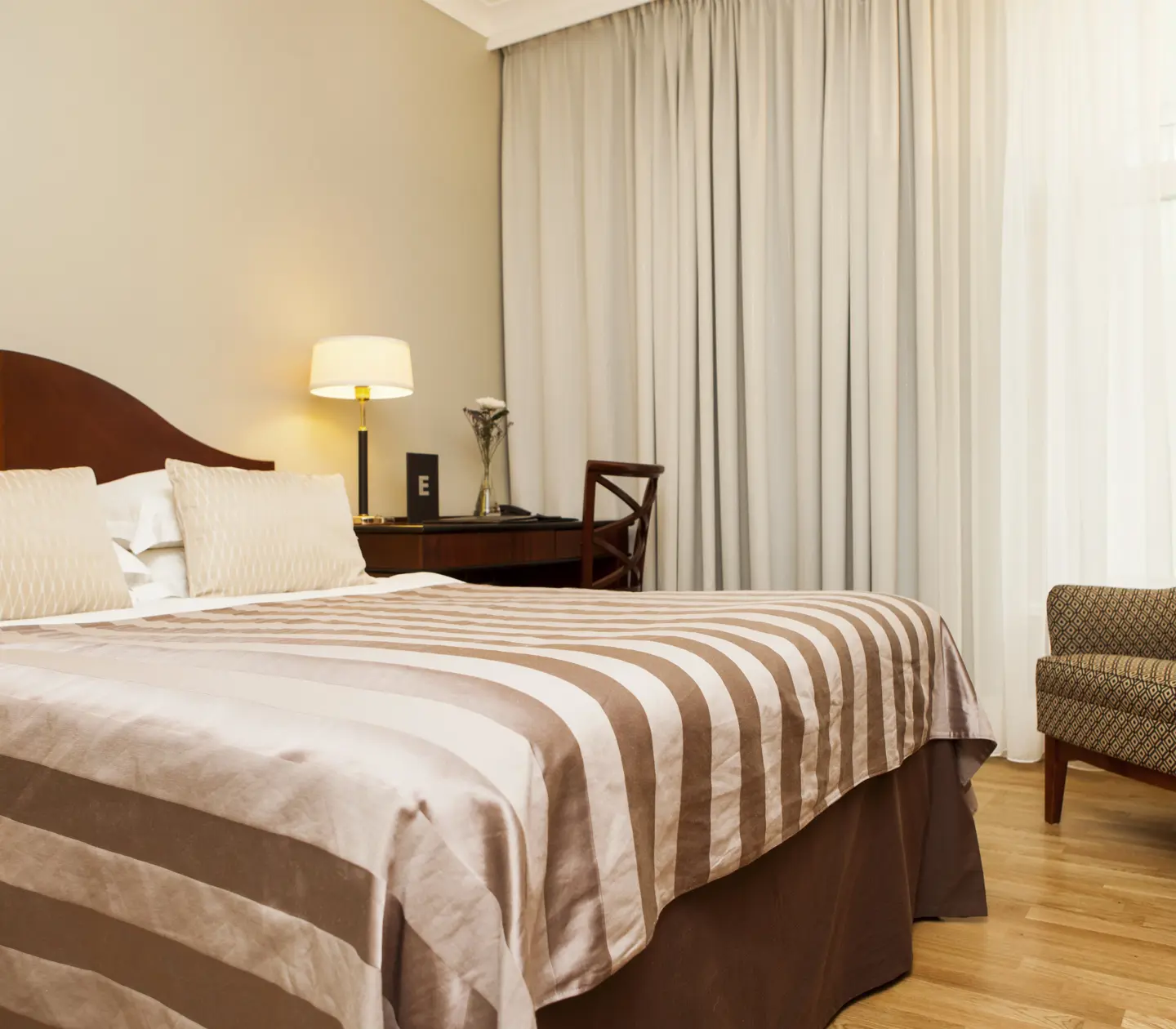 Hotel room with double bed, armchair and curtains