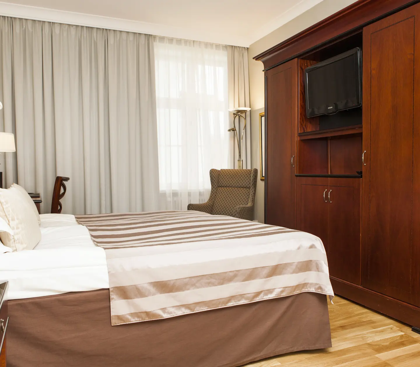 Hotel room with double bed, armchair and curtains