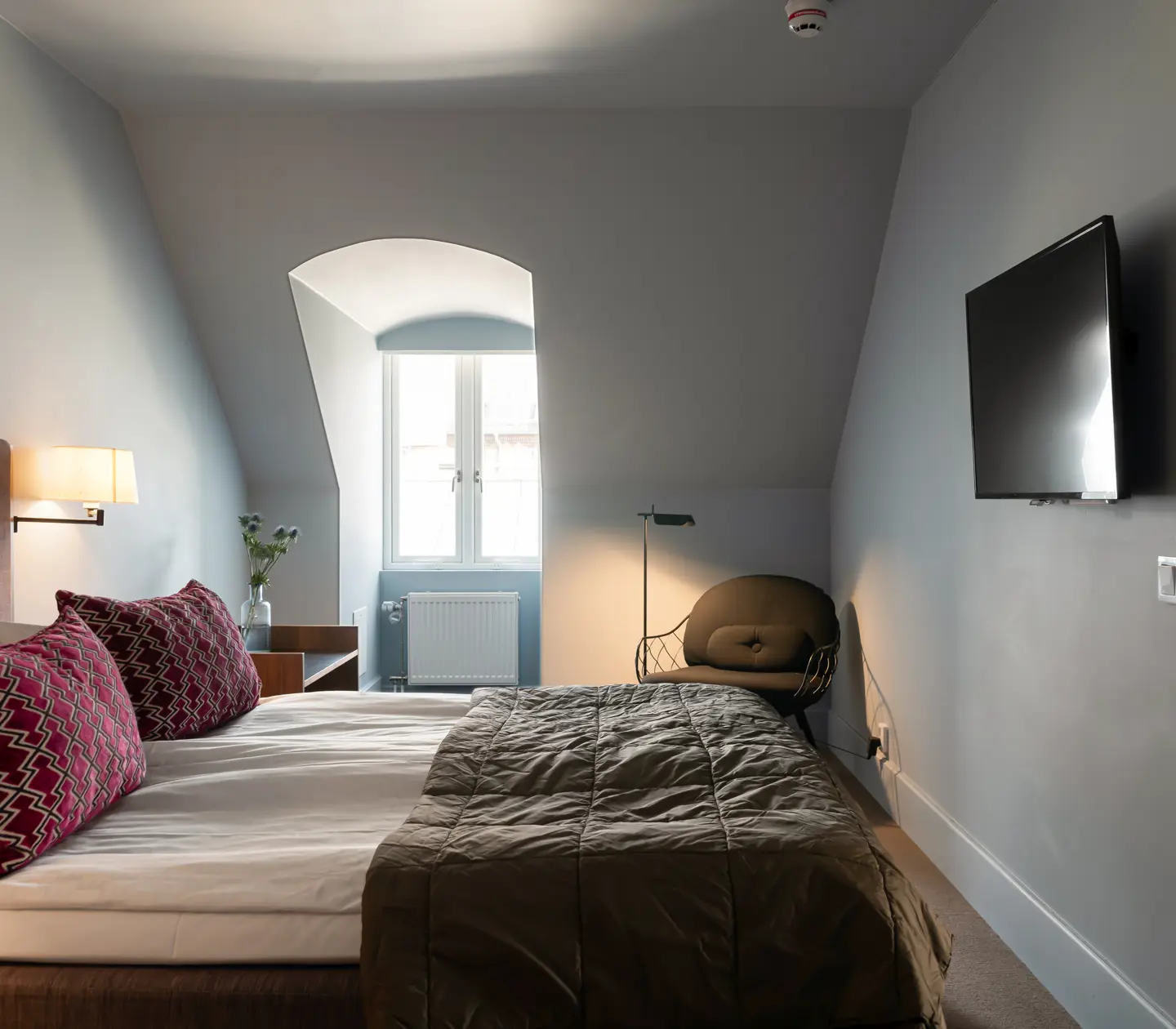 Suite with double bed, bedside lamps and sloping walls