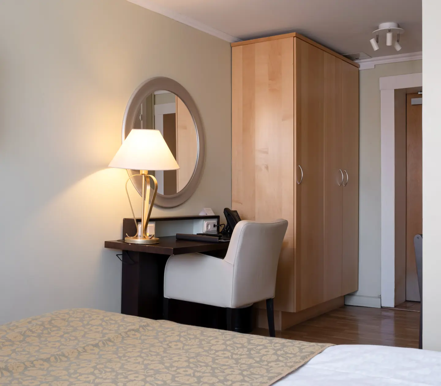 Hotel room with desk, round mirror and wardrobe