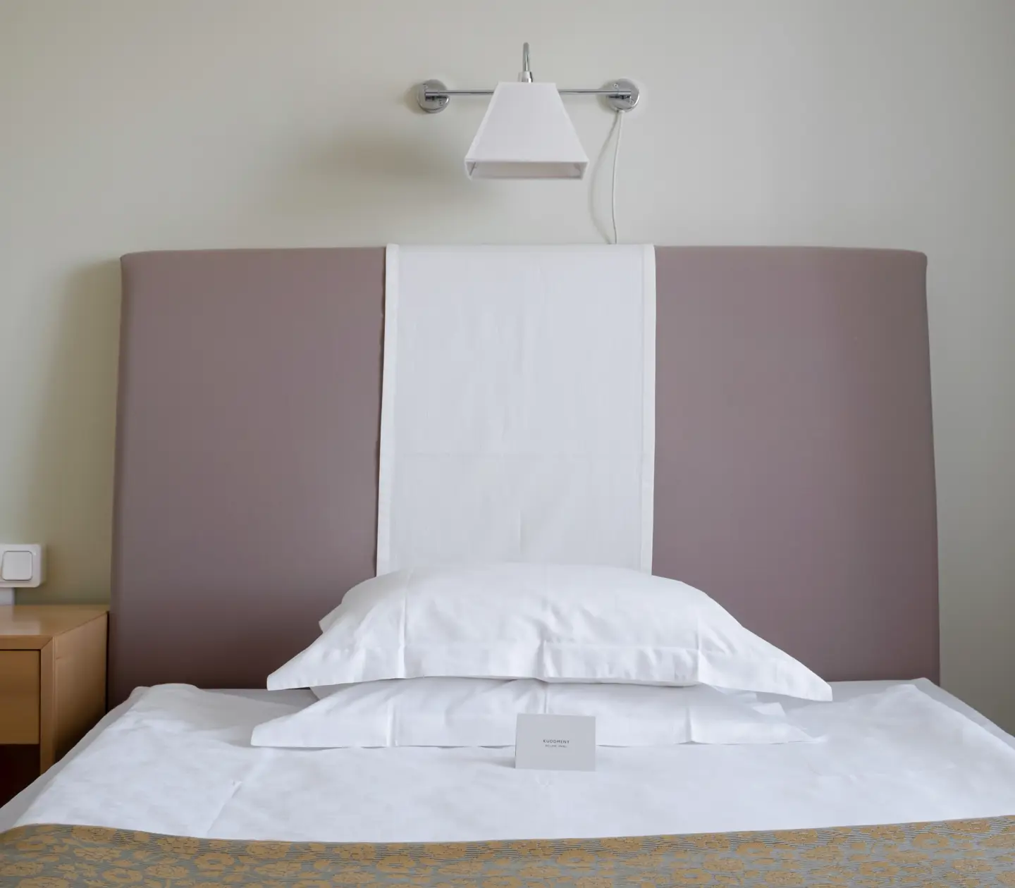Hotel room with bed, bedside lamp and bedside table
