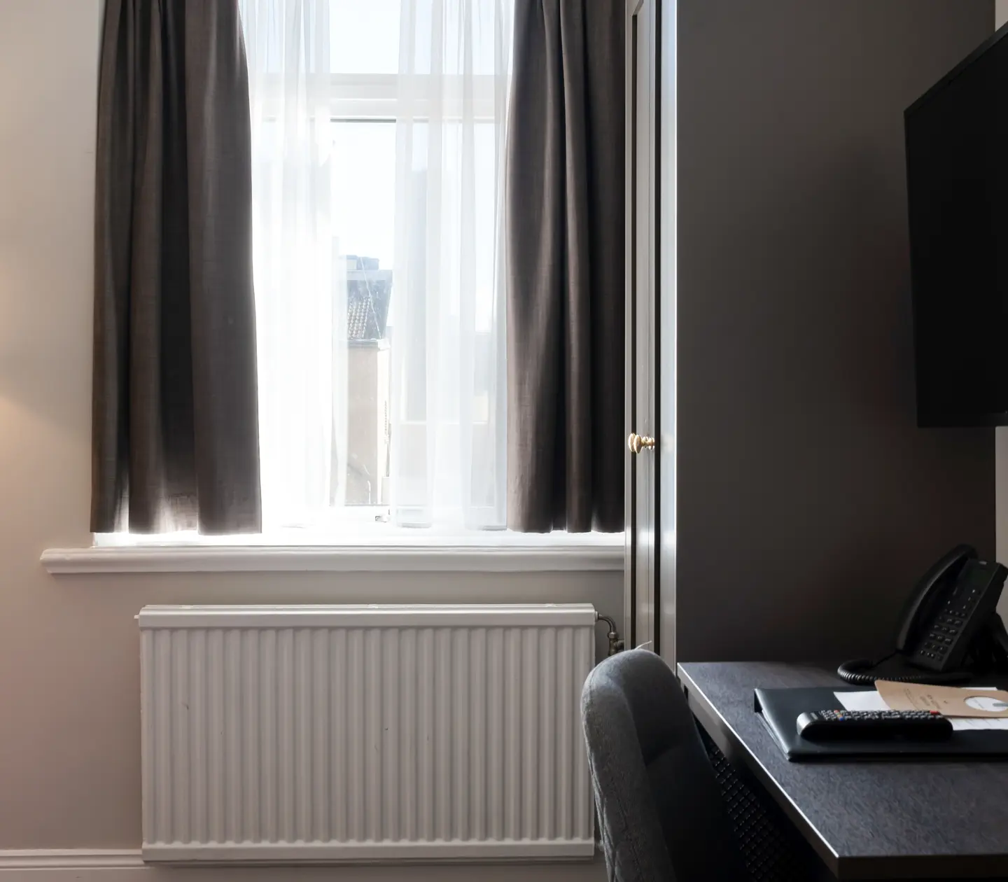 Hotel room with window, desk and wardrobe