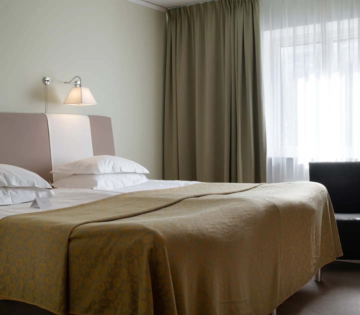 Hotel room with bed, armchair and curtains