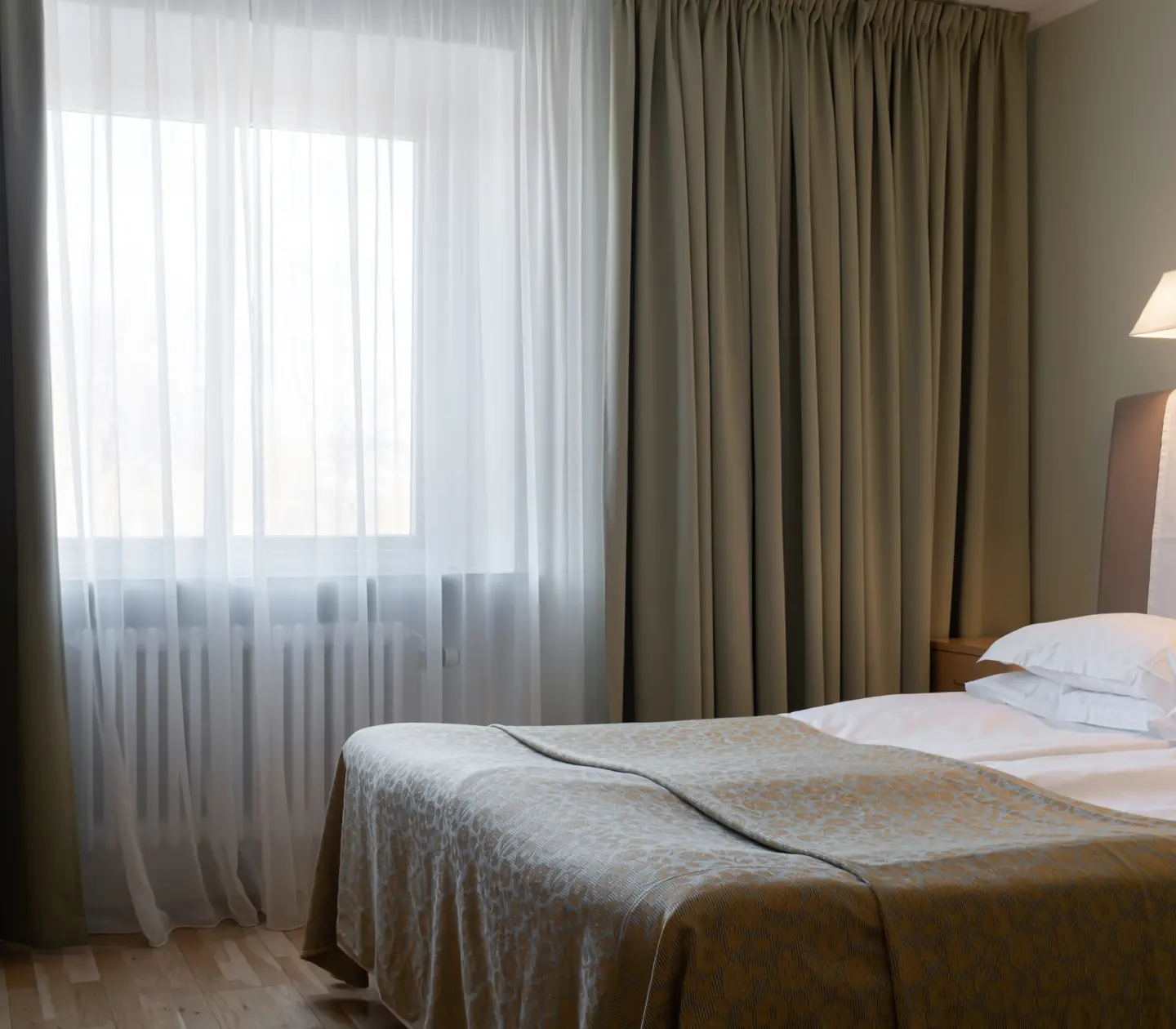 Hotel room with bed, bedside lamp and window