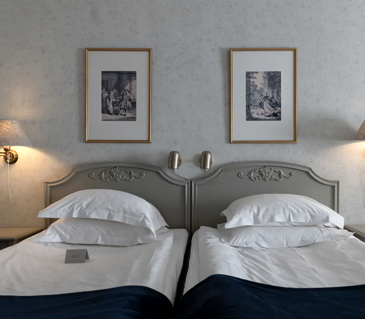 Hotel room with bed, bedside lamps and paintings