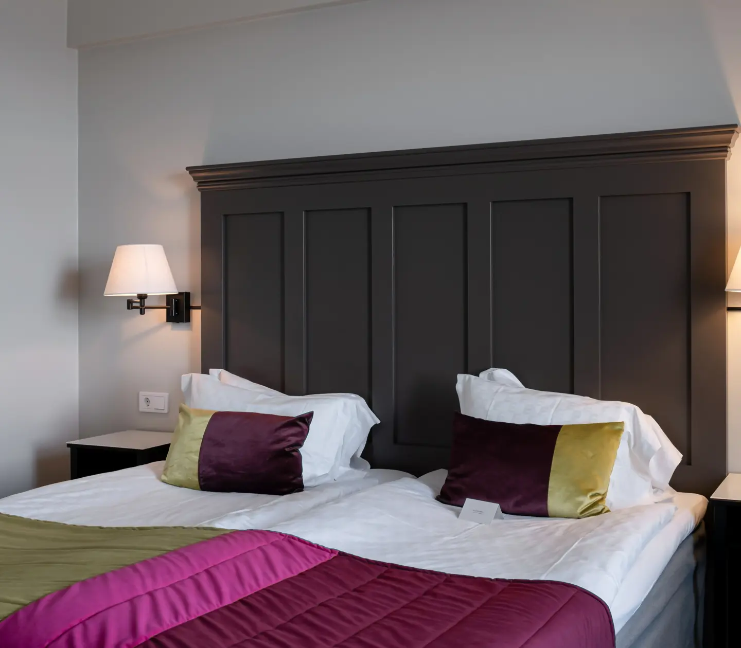 Hotel room with bed, large wooden headboard and painting